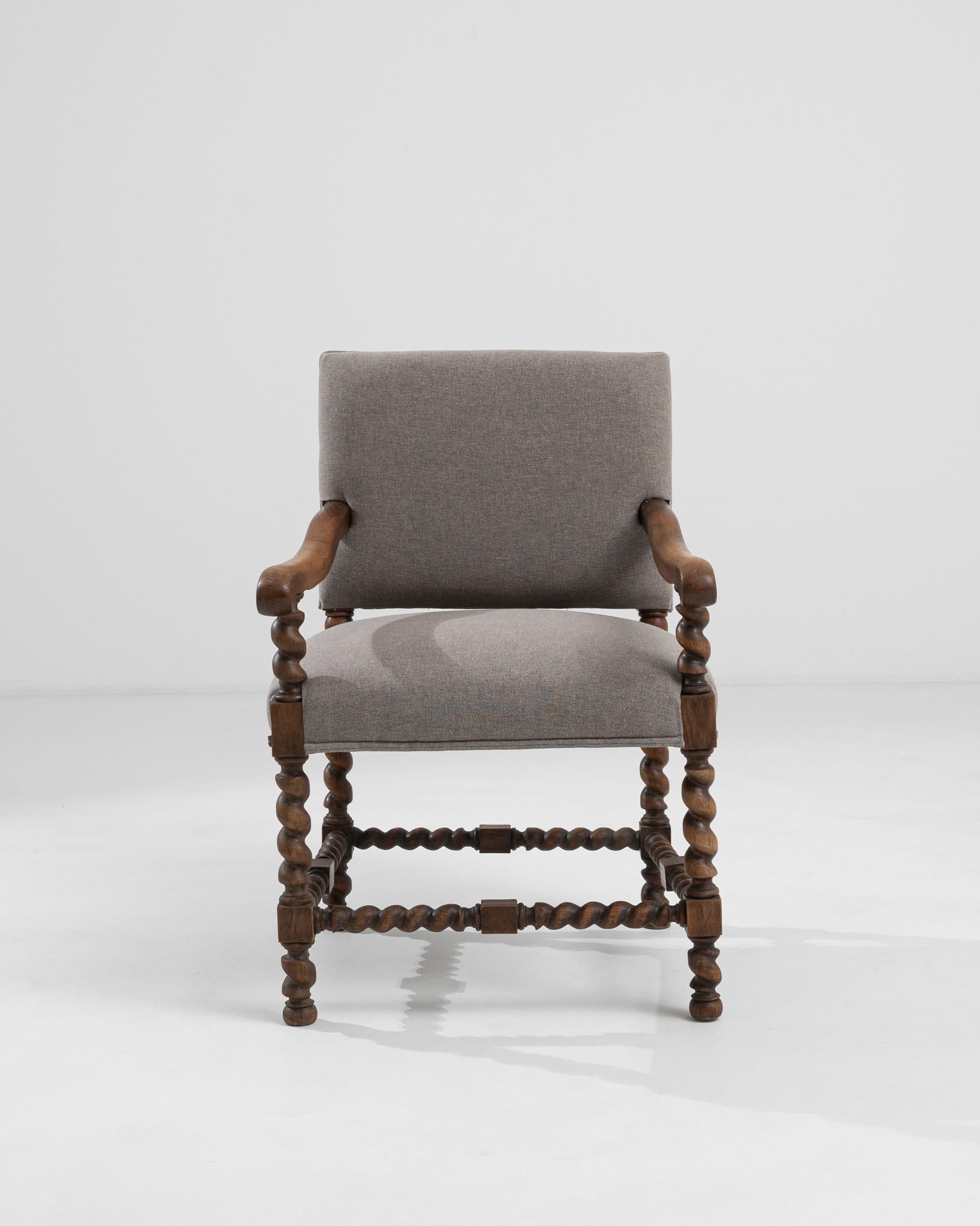A hardwood armchair with an upholstered seat and backrest from France, circa 1910. A warm and pleasing glow emits from the rich brown oak that composes this elegant chair. The throne-like frame is embellished with elaborate carving, fashions of the