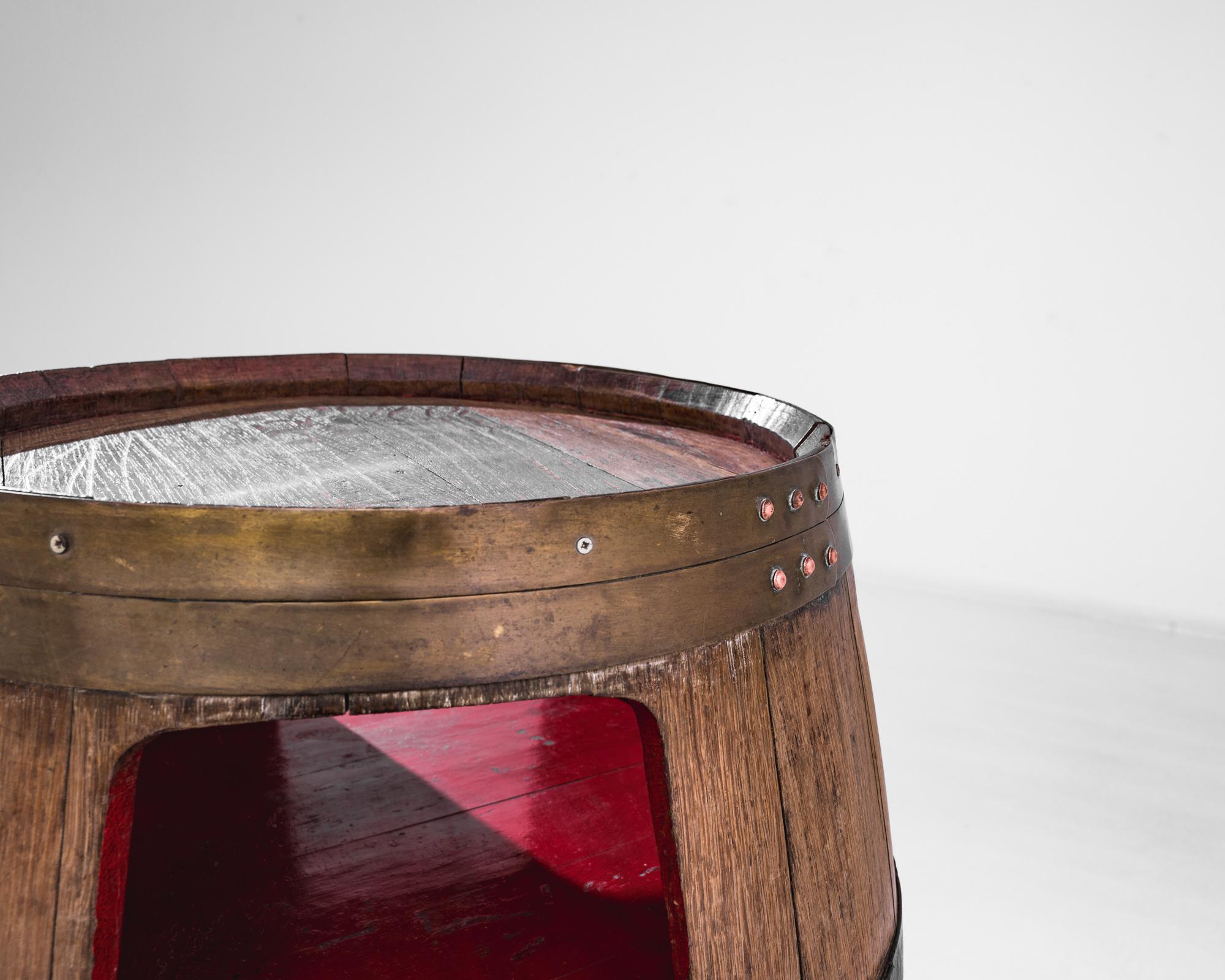Discover the rustic charm of this authentic 1910s French wooden barrel, a piece that brings the essence of the French countryside into your space. Crafted with care from sturdy wood, this barrel features original metal banding that speaks to its