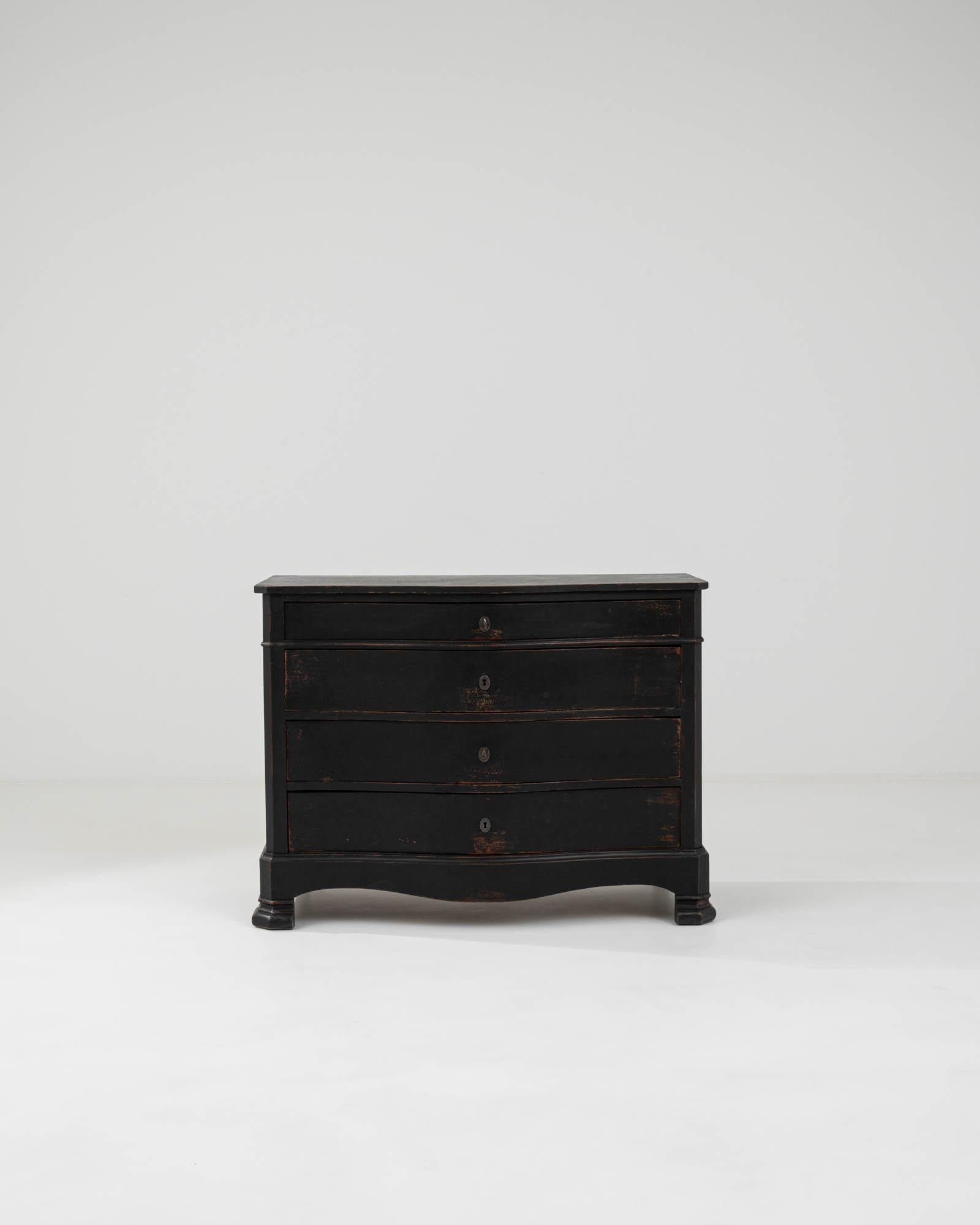 Discover a storied masterpiece for your home with this 1910s French Wooden Chest of Drawers. Echoing the robust yet refined style of the early twentieth century, this piece is graced with a rich, ebony patina that highlights its age and the