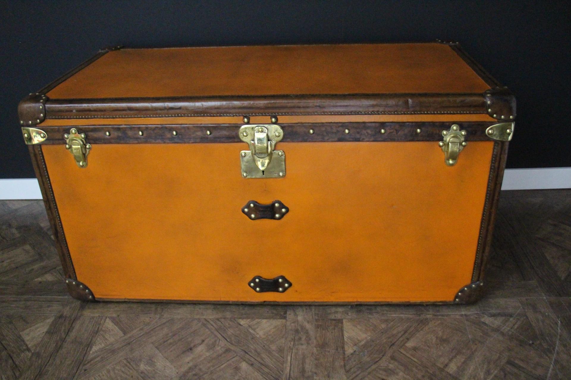 Este inusual baúl grande de Louis Vuitton presenta una hermosa lona naranja, todo el tapizado de cuero en color chocolate, grandes asas laterales de cuero repujado LV, así como cerradura, cierres y tachuelas de latón estampado Louis Vuitton. Tiene