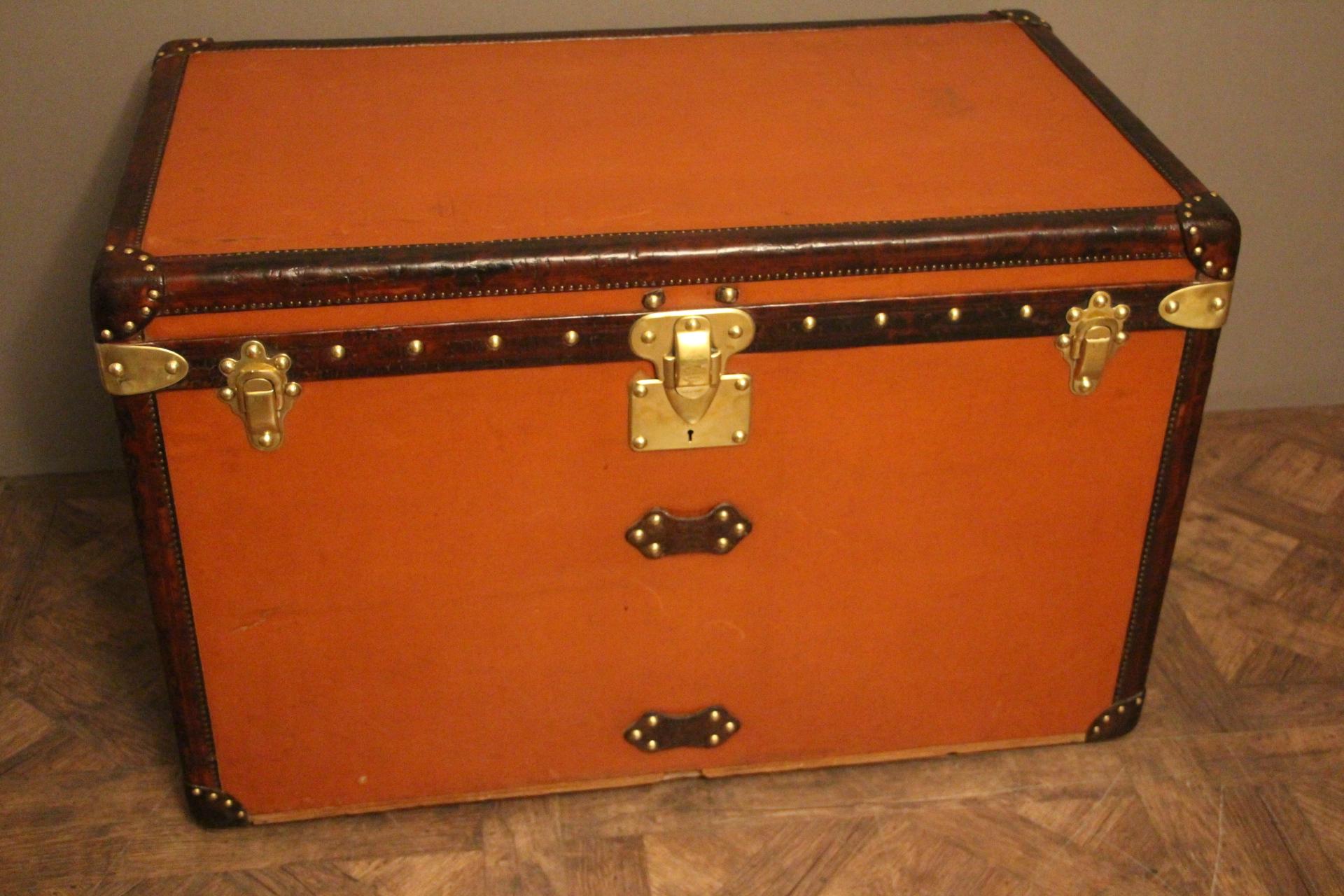 This unusual orange Vuittonite canvas courrier trunk has got all leather trim and handles, all brass stamped LV studs and brass locks. iI has a beautiful original warm orange patina.
Its interior is all original too with beige linen, removable