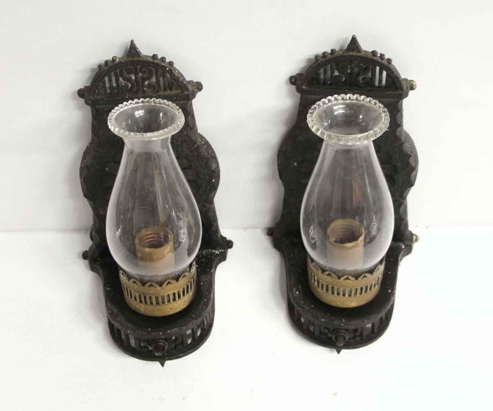 1910s pair of cast iron wall sconces with clear glass chimney shades. Done in an Arts & Crafts style.
