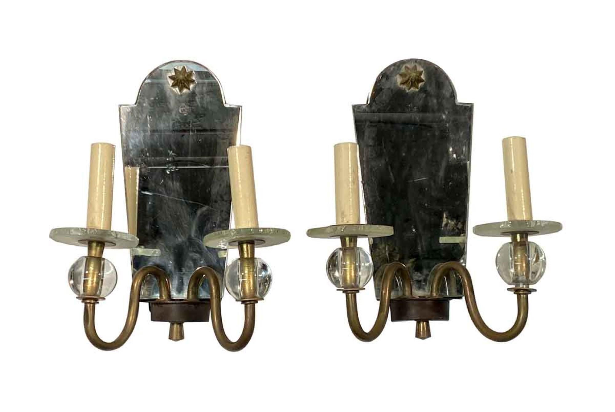 1910s French pair of mirrored wall sconces with two slender brass arms and a brass star motif. This can be seen at our 400 Gilligan St location in Scranton, PA.