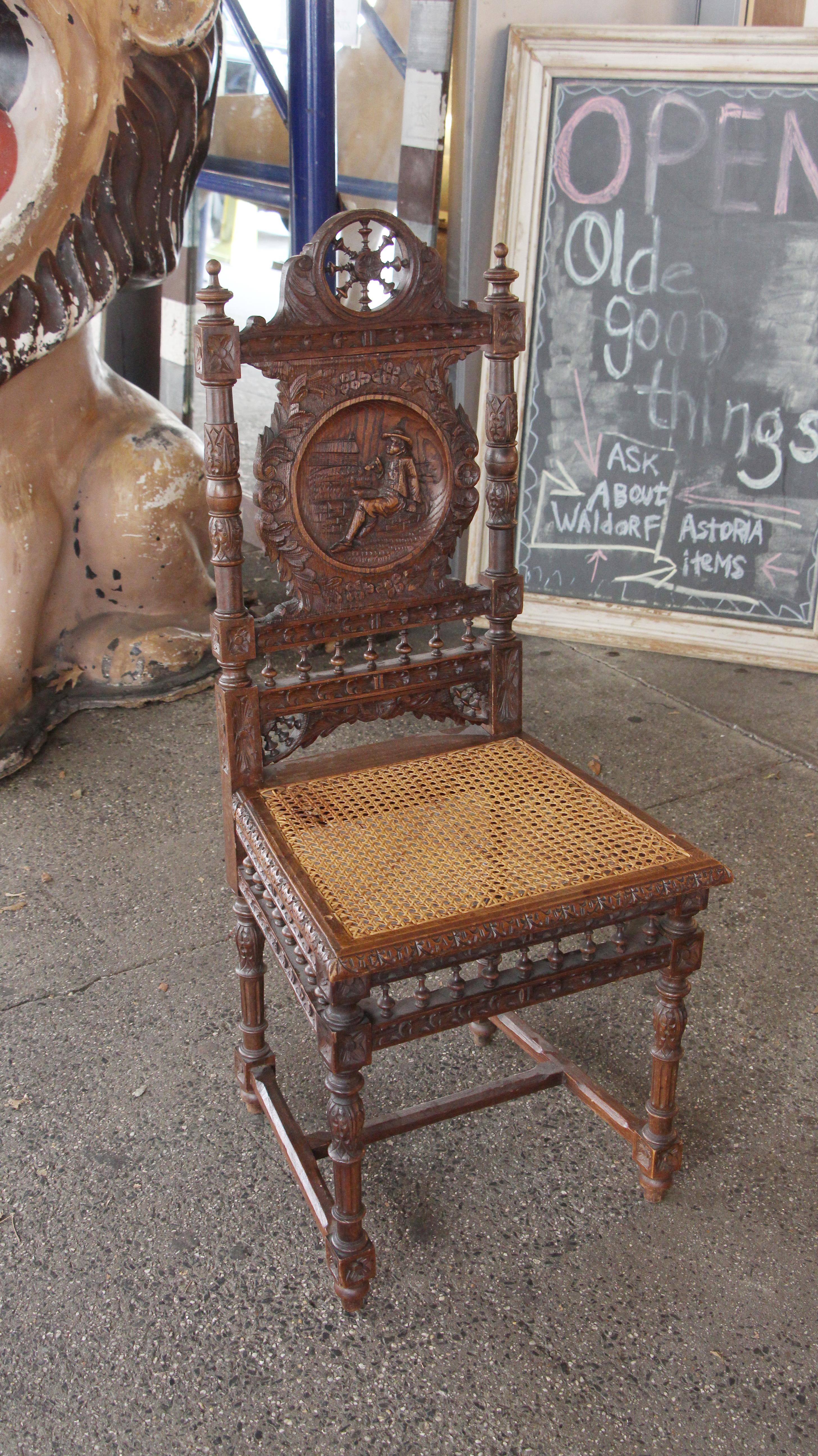 Dark wood tone carved English Renaissance style chairs with a wicker seat. Each chair back has a different carved figural scene. The set is in overall excellent condition, except one of the wicker seats has some damage. The wicker is not original to