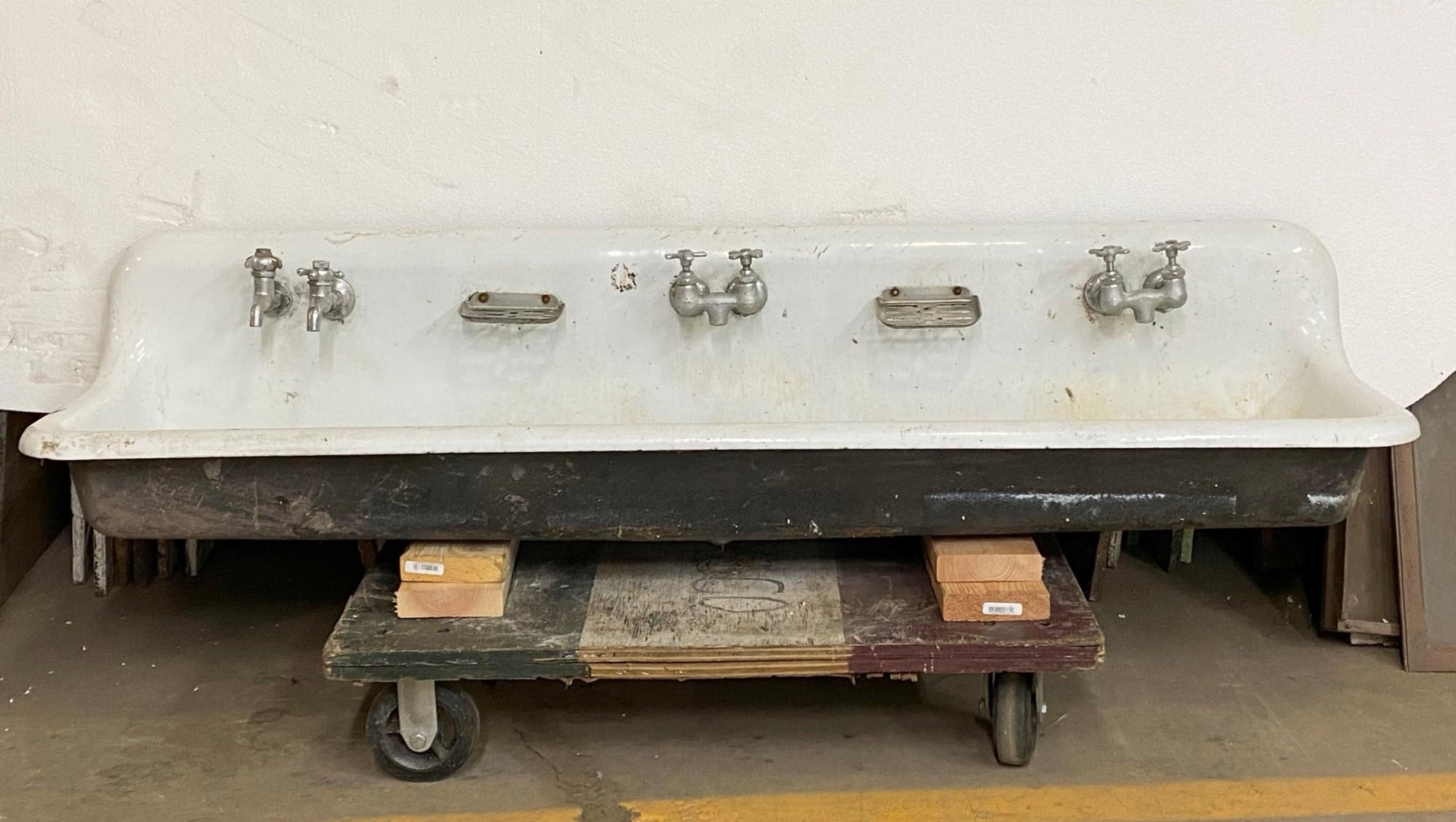 White porcelain over cast iron trough gang sink. Perfect for a farm house or work room with an industrial factory feel. The original soap dishes and faucets are included. 3 in. spread center to center. This can be seen at our 400 Gilligan St