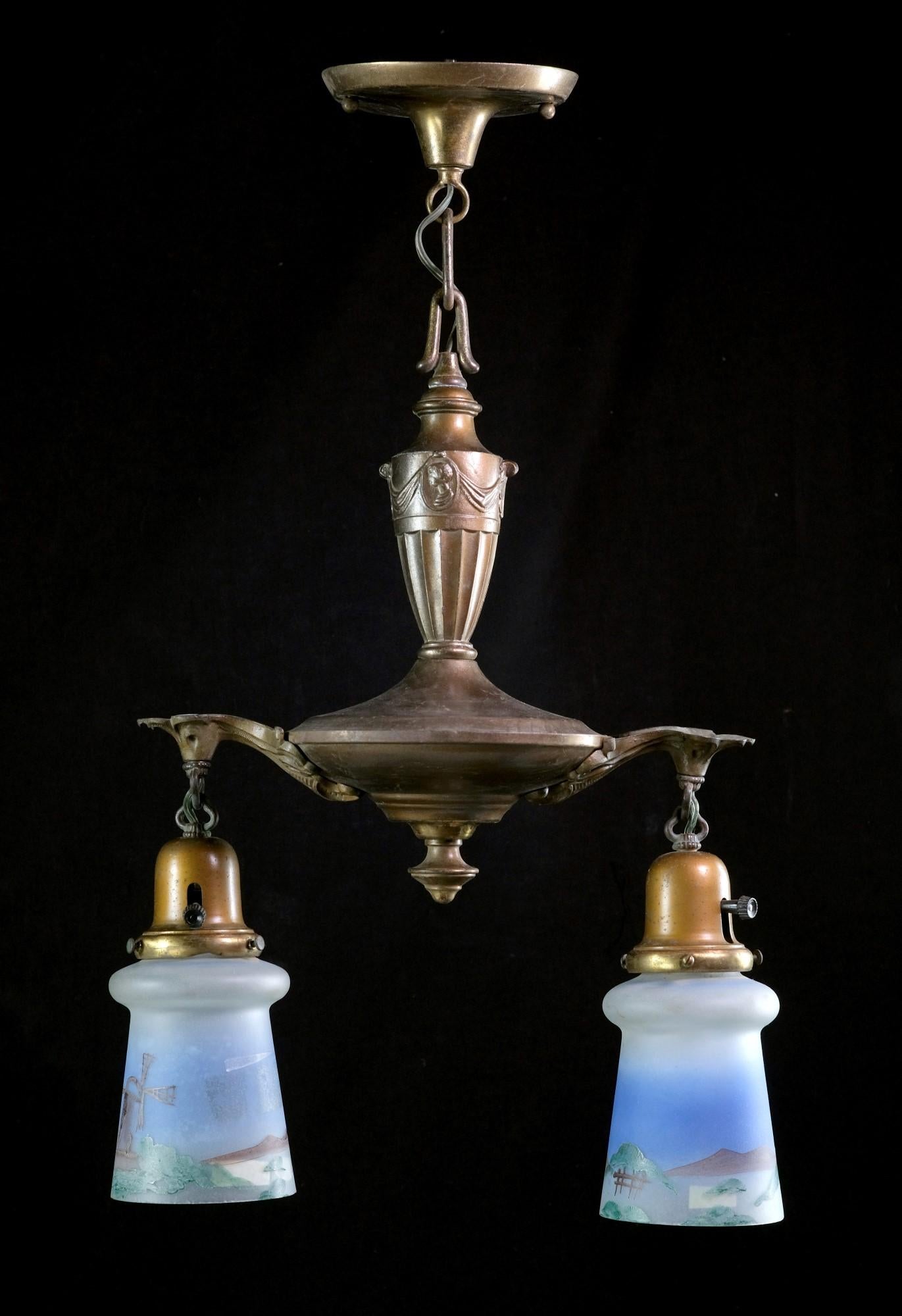 1910's Ornate brass pendant light with two hanging down lights featuring hand-painted shades. This brass light has a Victorian style, and the glass shades are hand-painted with scenic details. The price includes restoration. This can be seen at our