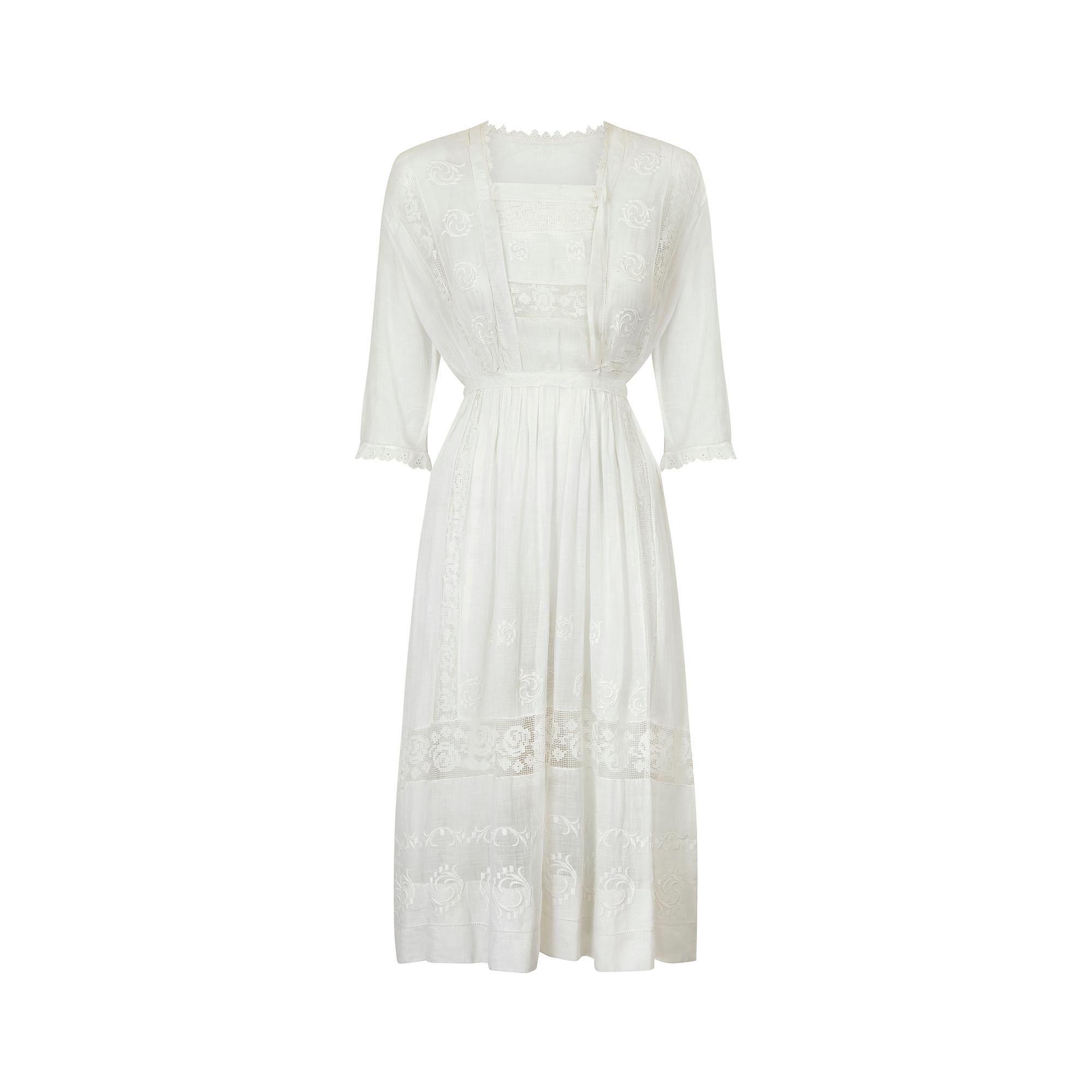 This late 1900s to early 1910s cotton whitework midi dress is in great wearable condition.  Fashioned from lightweight cotton with filet lace rose design inserts throughout the chest, cuffs and hem of the dress creating a beautiful Edwardian look.