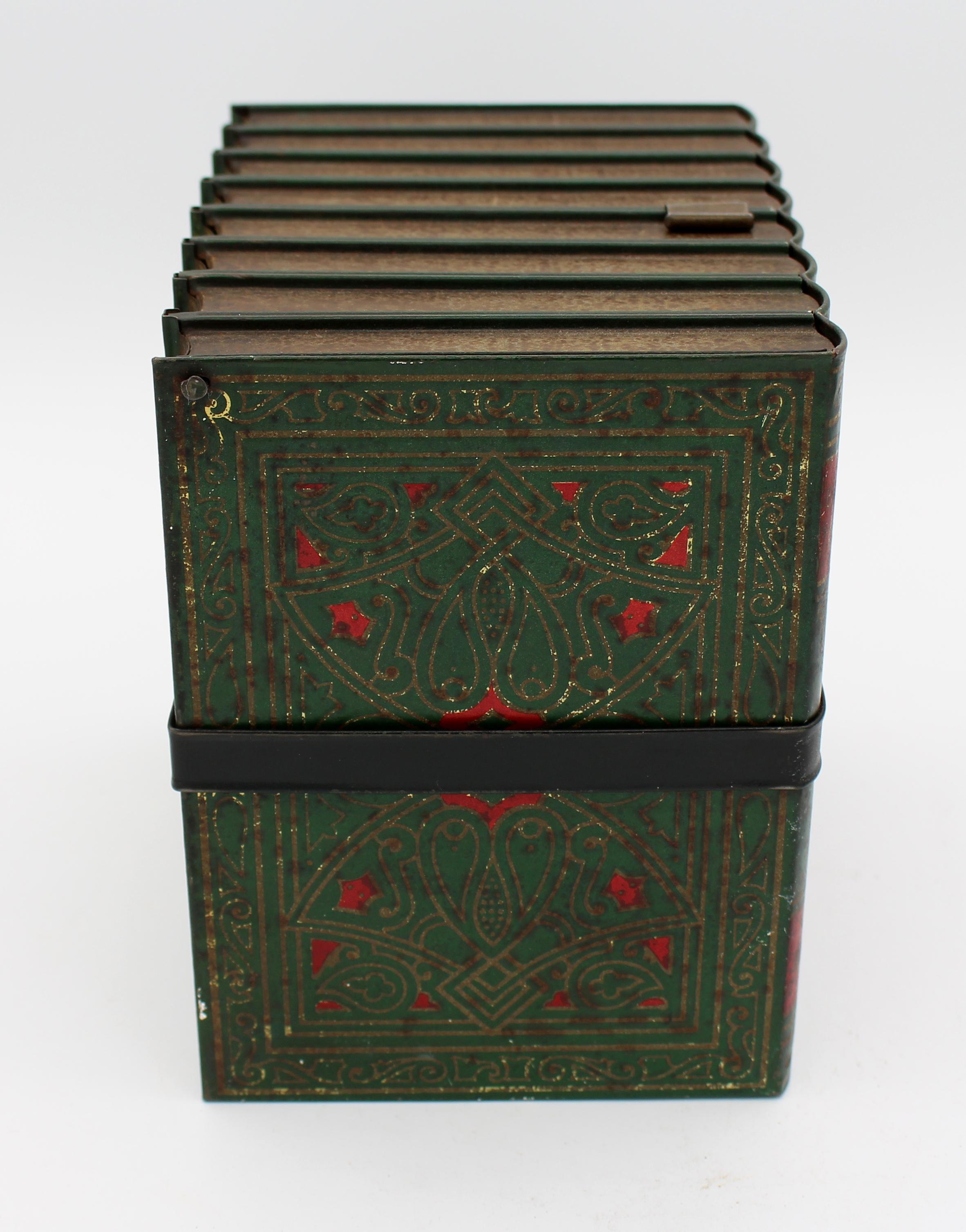 Boîte en fer blanc pour faux livres de Huntley & Palmer, 1911, anglais. Sous la forme d'un groupe de romans à bretelles de Charles Dickens en peinture ancienne verte & rouge avec travail de dorure et bretelle noire. Usure générale correspondant à