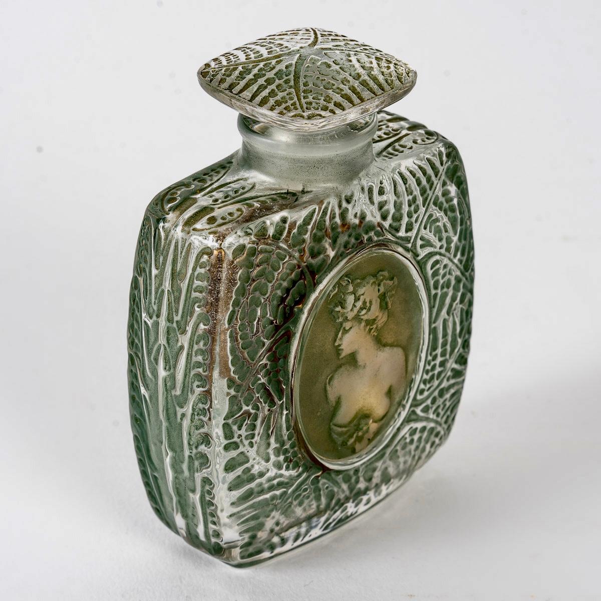 Perfume Bottle “Fougeres” made in frosted glass with green patina and applied medallions on gold foil by René Lalique in 1912.
Molded signature on bottom.

Perfect condition. Superb patina.
Extremely rare and desirable bootle. 

Height: 9