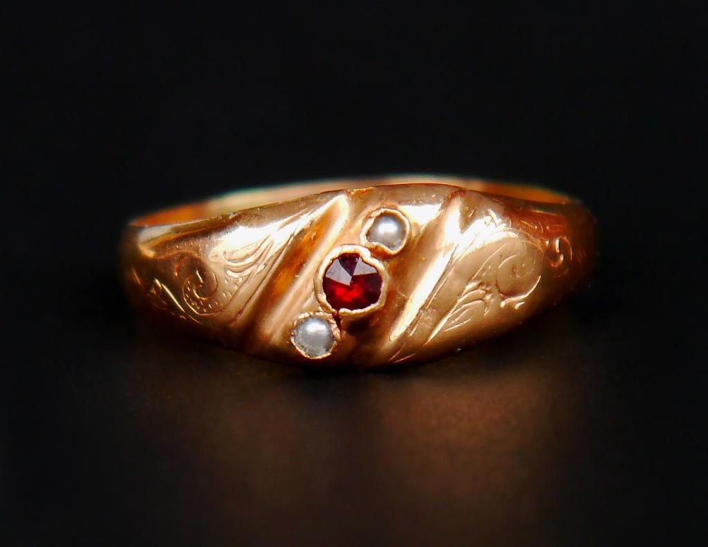 Antique Ring with two natural Seed Pearls and one rose cut Garnet of Pyrope variety set in solid 18K Gold band with hand - engraved decor on the shoulders.

This ring was made Sweden in 1912 ( mark K7 = 1912) Makers marks worn ; city of Eskilstuna ;