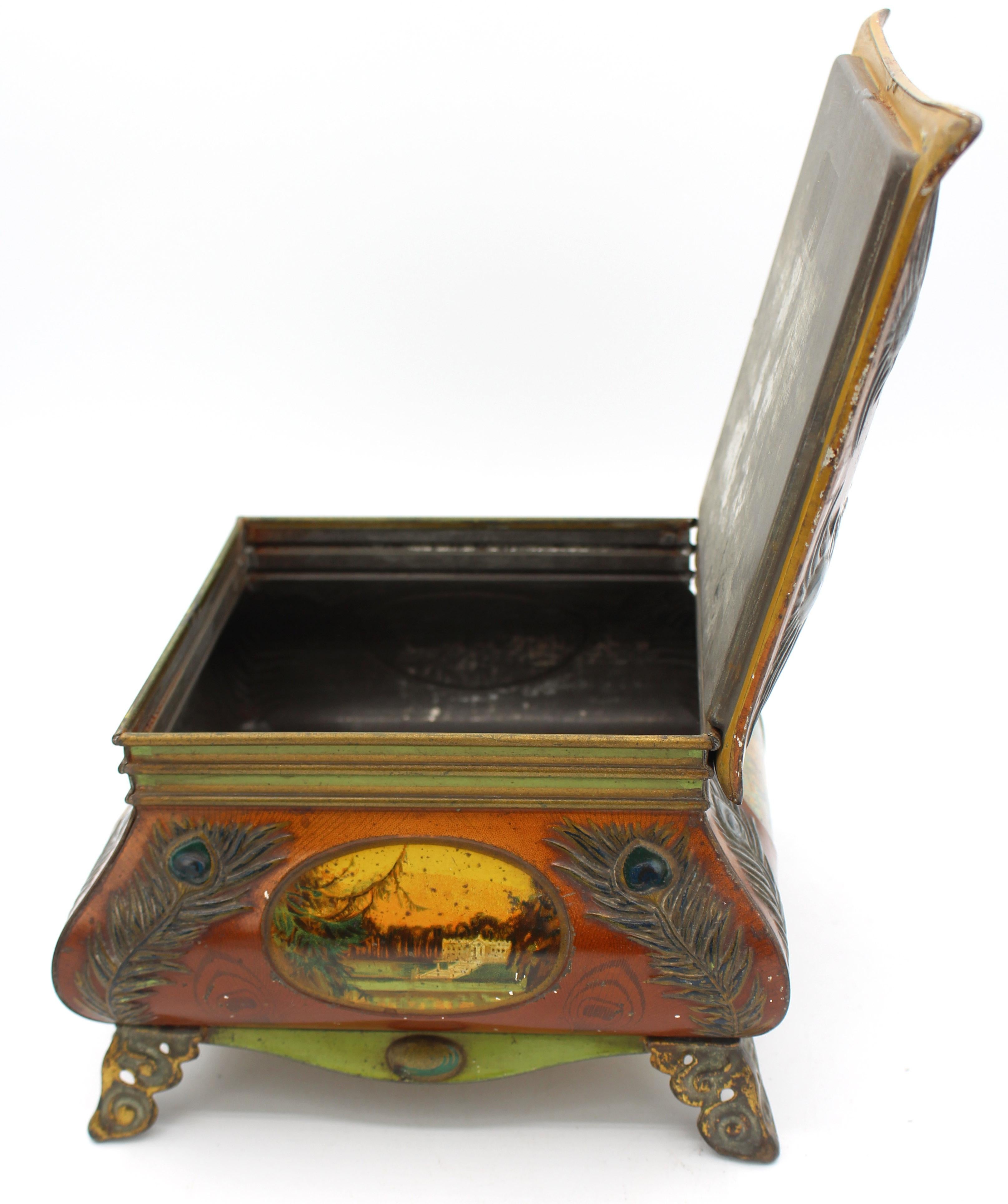 1913 jährliche Huntley & Palmers Tischplatte Box Keksdose. Kühn geschwungene Form - die Schachtel ist mit Pfauenfedern und romantischen Schultafeln verziert. Auf verschnörkelten Füßen stehend. Volles & extravagantes Huntley & Palmers Abzeichen auf