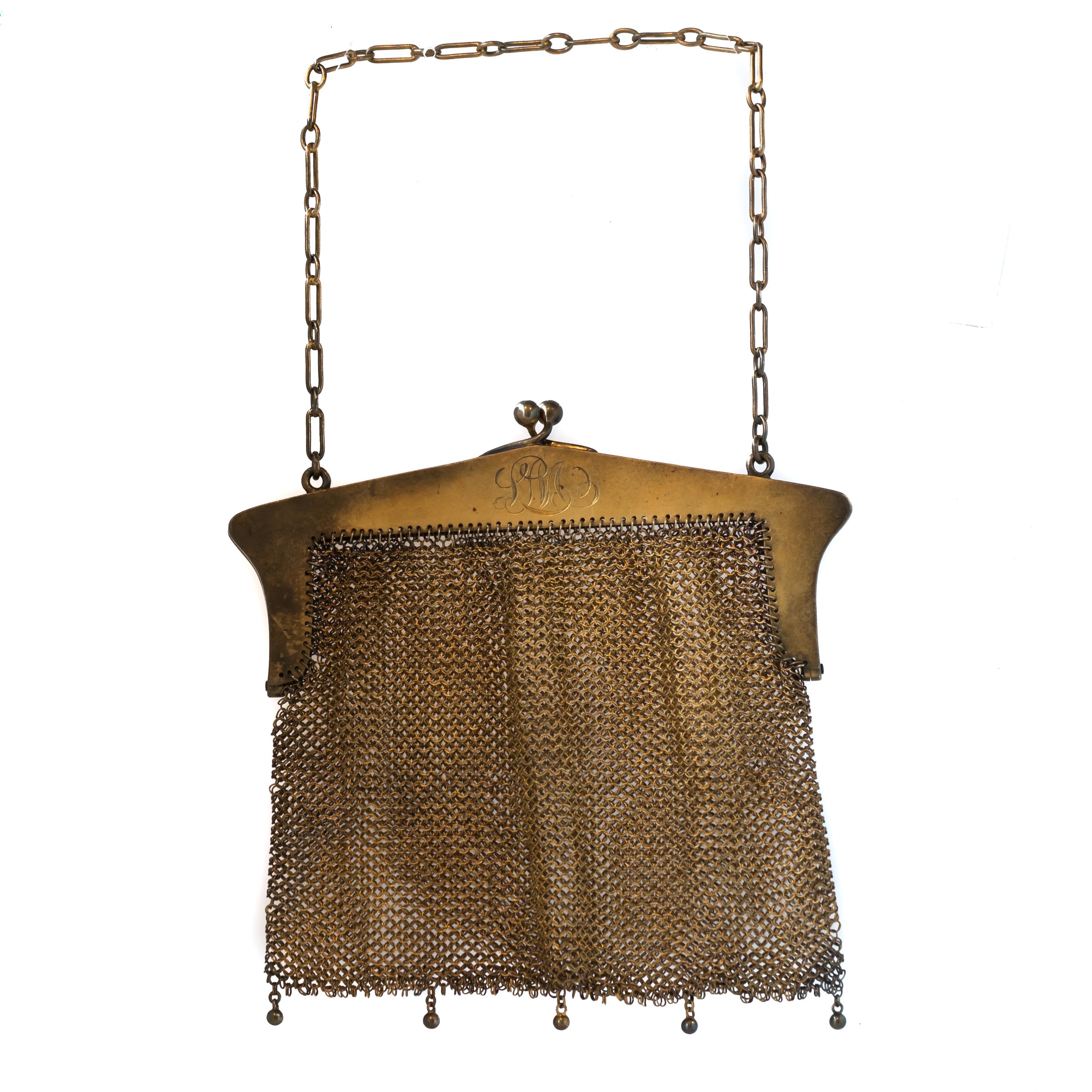 1914 Art Nouveau Mesh Purse - Sterling Silver

Features:
Sterling Silver with Gold Wash, Metal has accumulated heavy visible patina 
Mesh Body with a Floral Design Frame
Link Chain Top Handle and 5-Bead Fringe Bottom 
Hinged Opening
Inner Frame is