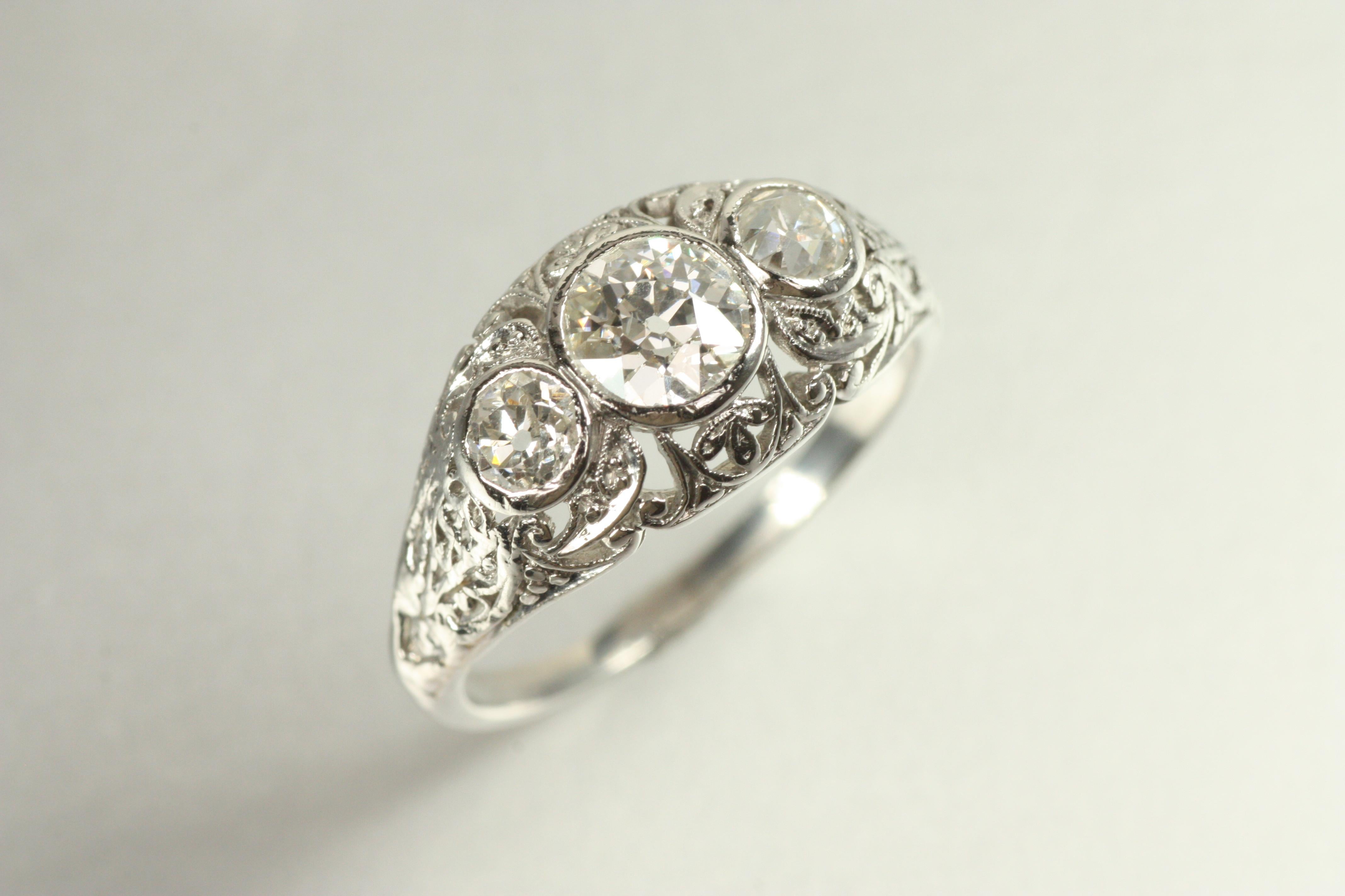 A true antique treasure, this 1915 three-stone engagement ring embodies the romance of the Edwardian era. Exquisite filigree detailing frames three old European cut diamonds (0.87cttw), each capturing the light with an enchanting vintage sparkle.