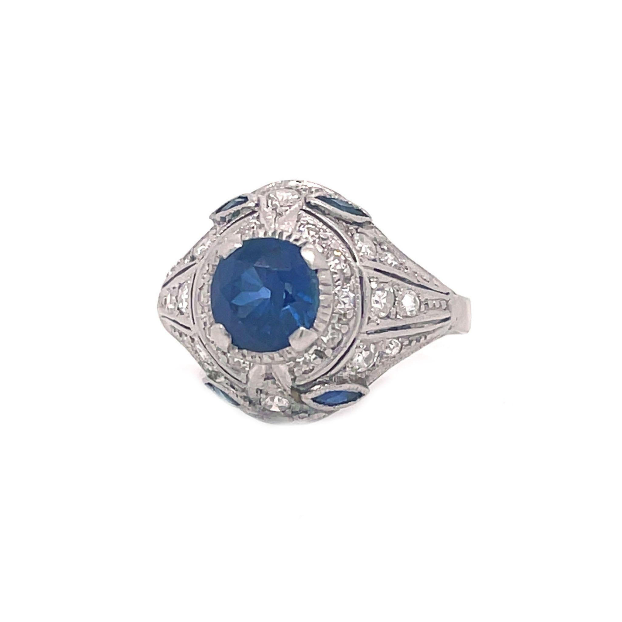 This is an absolutely breathtaking Art Deco ring set in platinum with bright sparkling diamonds and a rich blue sapphire! The Art Deco influence is clear in the dramatic lines and gorgeous color contrast with this ring. The piercing blue sapphire