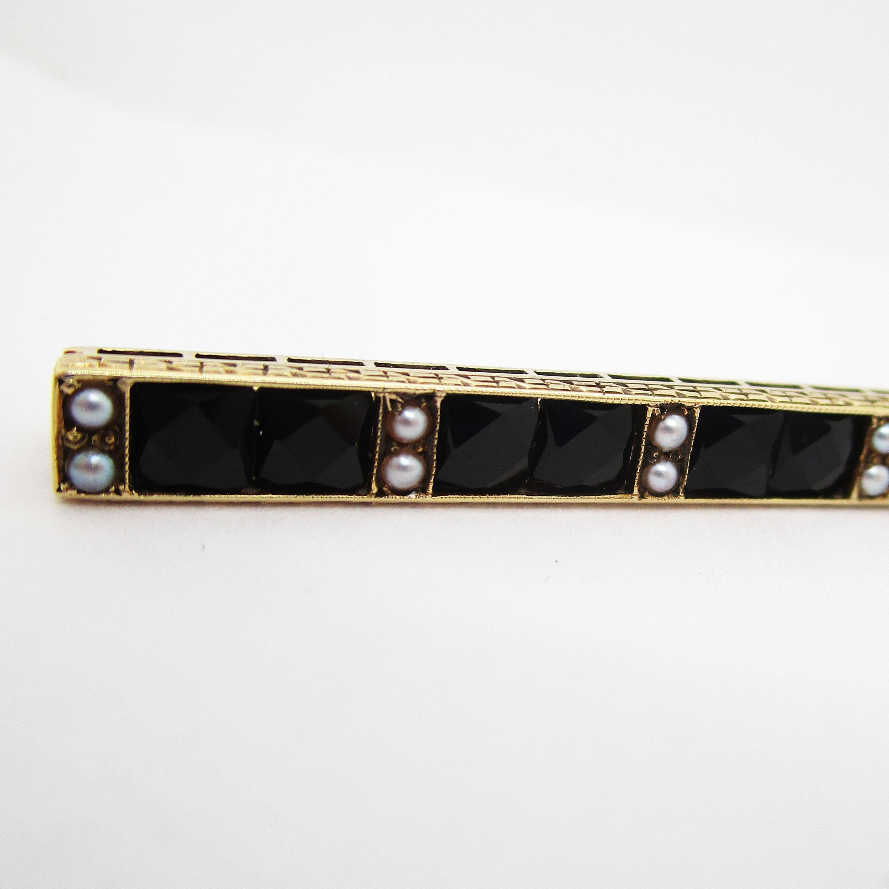 Dies ist eine atemberaubende Art Deco Bar Pin aus dem Jahr 1915 von Sloan & Co mit einer fantastischen Kombination aus französisch geschliffenen schwarzen Onyx, Saatperlen und 14k Gelbgold. Die dramatische Kombination aus geometrischem, facettiertem