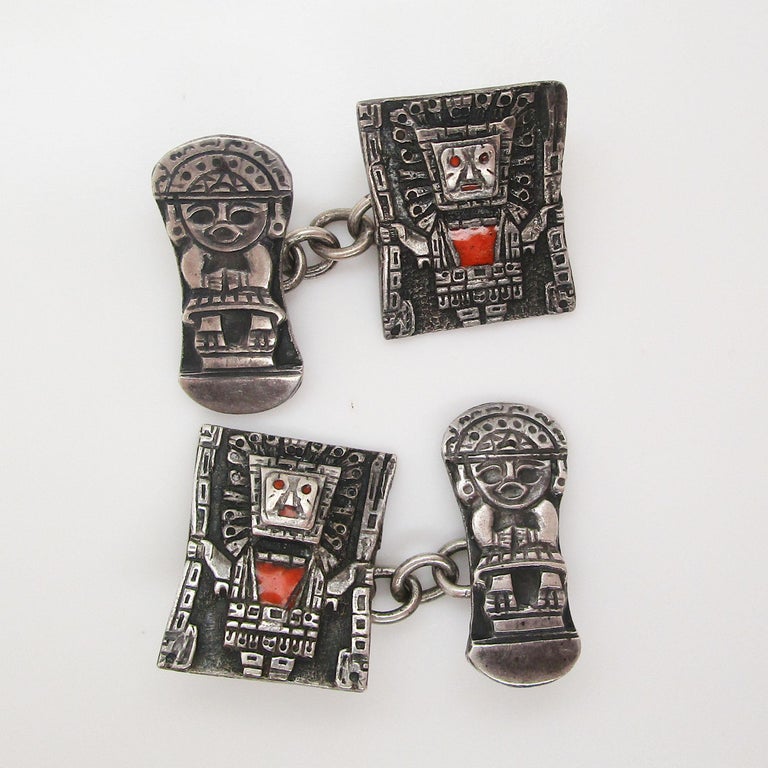 These are a magnificent set of Art Deco cufflinks in sterling silver with a fantastic Aztec design accented with bright orange enamel. The sterling silver serves as the perfect canvas for the dramatic geometric faces of what could be an Aztec god!