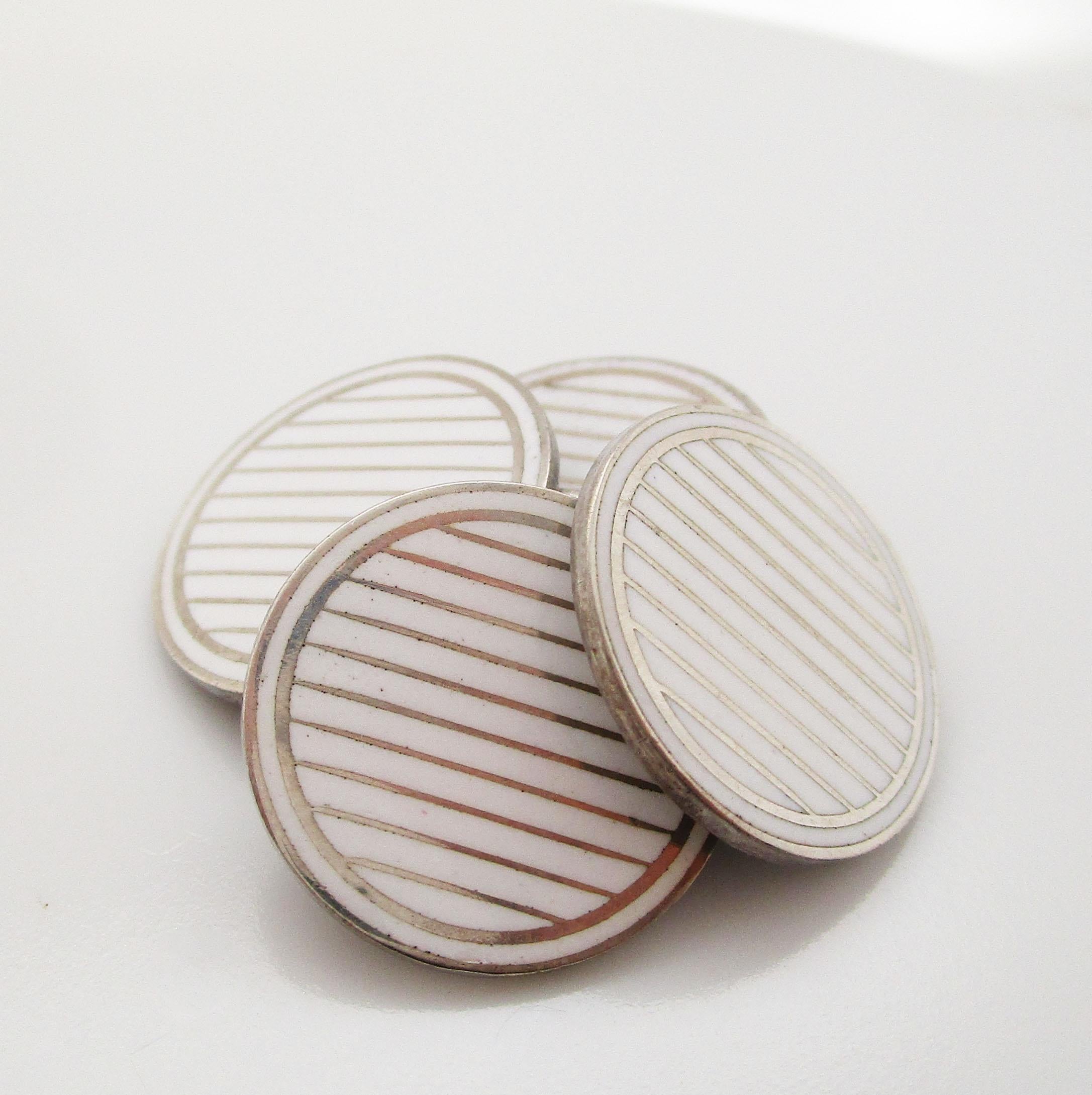 This fantastic set of Art Deco cufflinks is from 1915 and has a bold white striped panel that is the picture of Deco elegance. The cufflinks feature round oversized panels framed with a single white border filled by rows of white stripes. The enamel