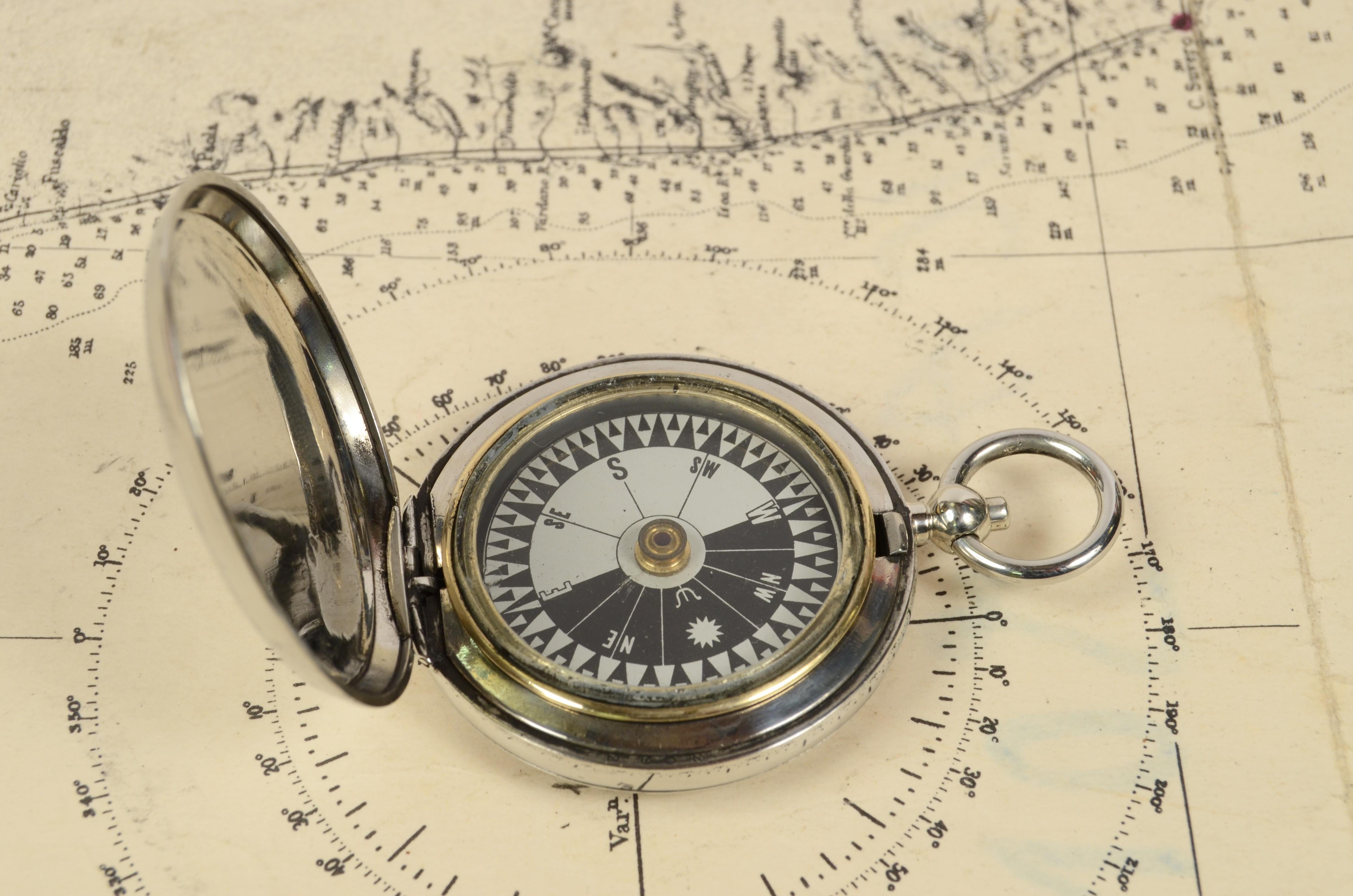 Pocket compass used by Britihs aviation officers made of chromed brass in the shape of a pocket watch, signed Dennison Birmingham V 104766 of 1916. The compass has a lid with snap closure with release button inside of the ring. Eight-winds compass