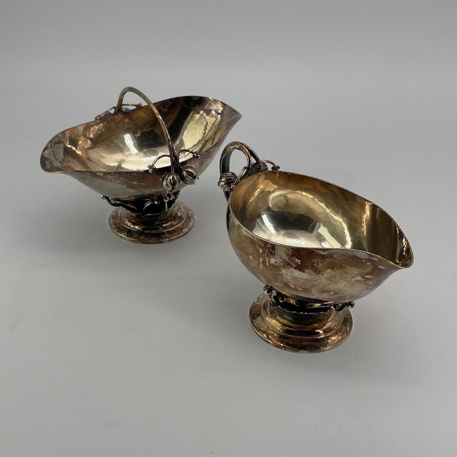 Präsentiert wie gefunden, nachlassfrisch. Dekoratives Milchkännchen- und Zuckerset aus Sterlingsilber, Modell #235B von Georg Jensen aus der Zeit um 1917. Ein schöner Korb mit Henkel und ein Sahnekännchen, die auf einer Reihe von Ästen und einer