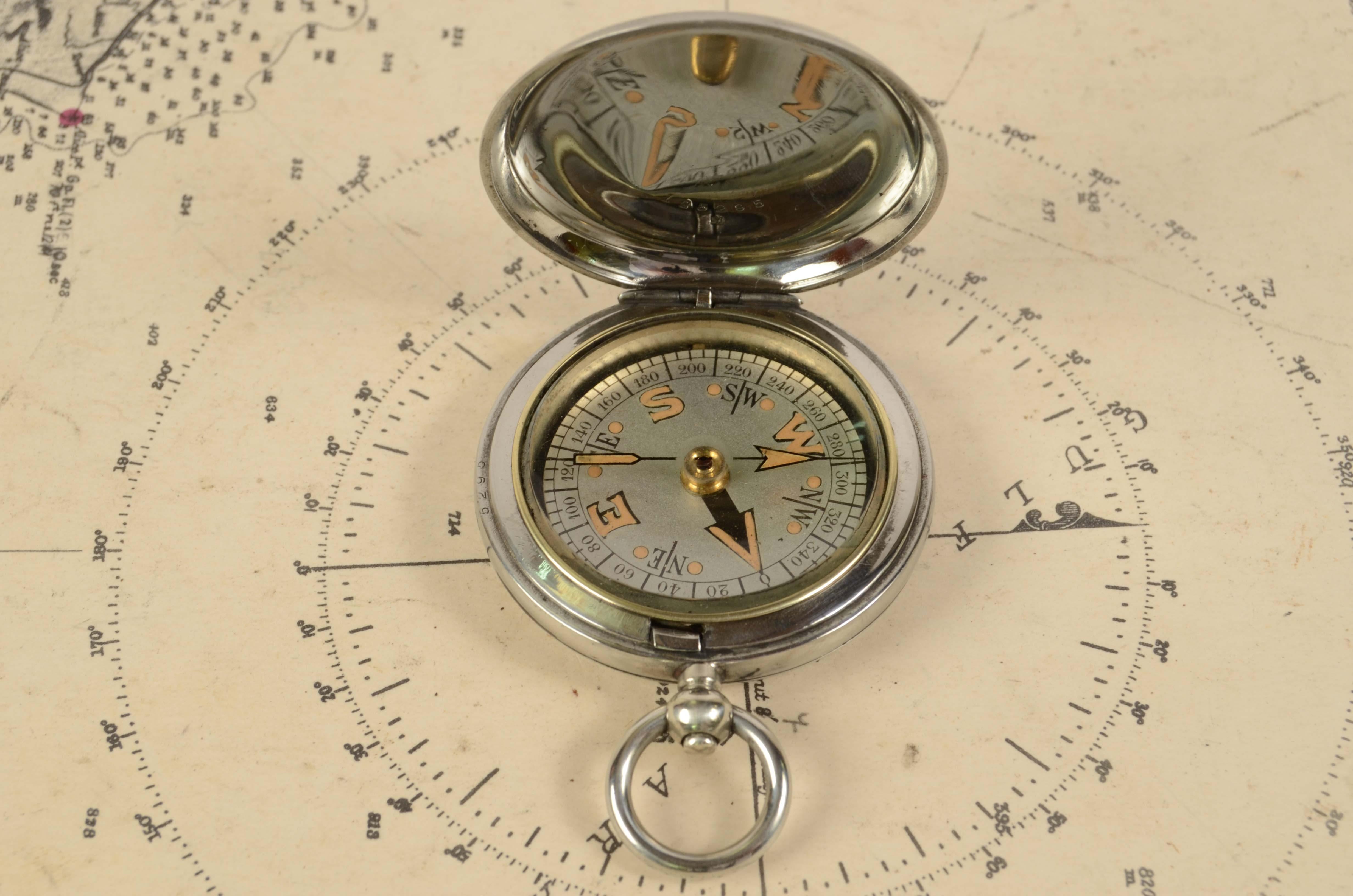 Pocket compass used by British aviation officers of chromed brass in the shape of a pocket watch, signed Dennison Birmingham VI 141115 from 1917. The compass has a snap-lock lid with release button inside the ring . Four-winds compass card complete
