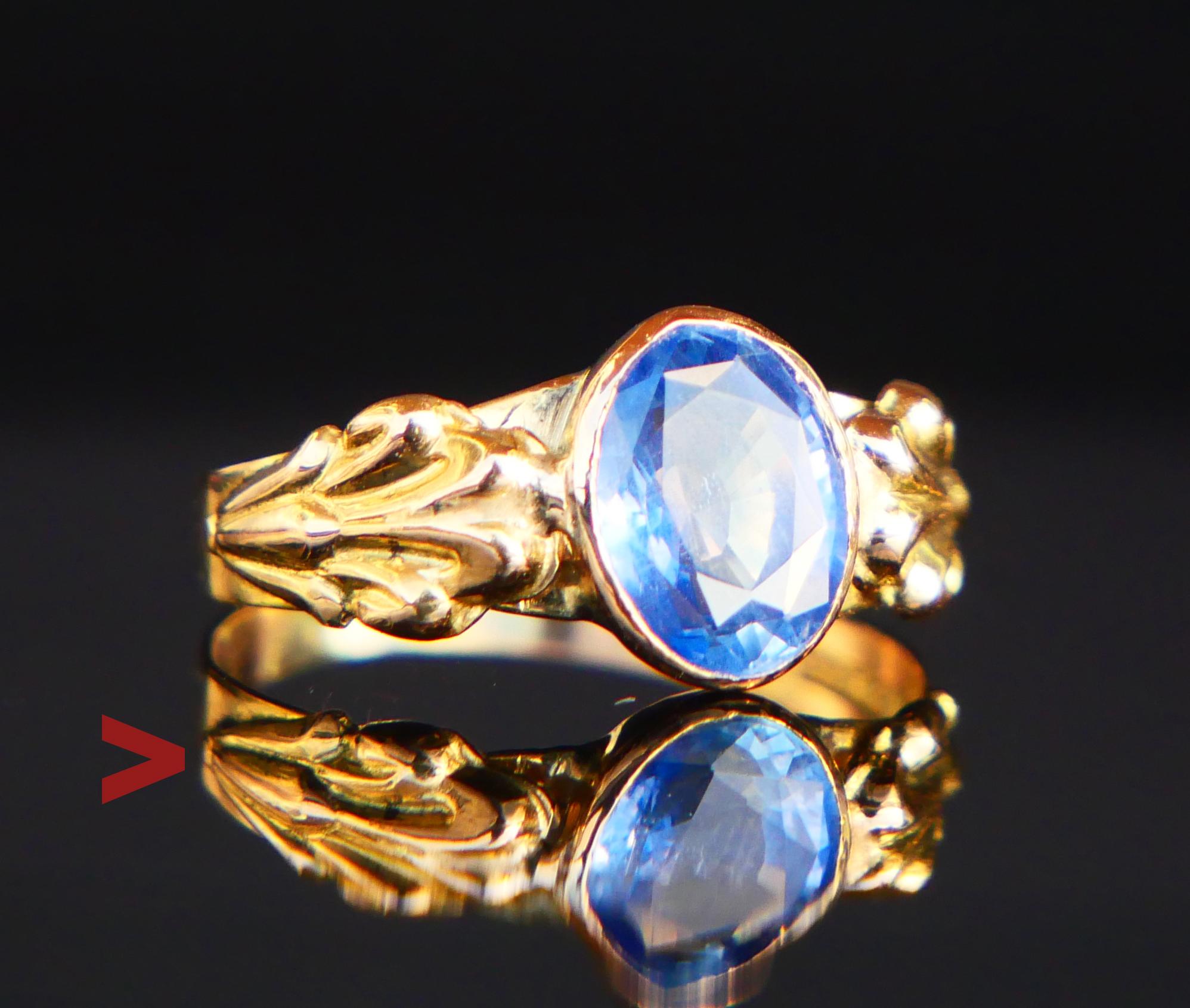 A Ring with carved shoulders featuring a bezel set natural Cornflower / Light Blue Sapphire of oval diamond cut 8 mm x 6 mm x 3.9 mm deep / ca. 1.5 ct. Light Blue Color, transparent stone - demonstrates some micro-inclusions and color zoning. Likely