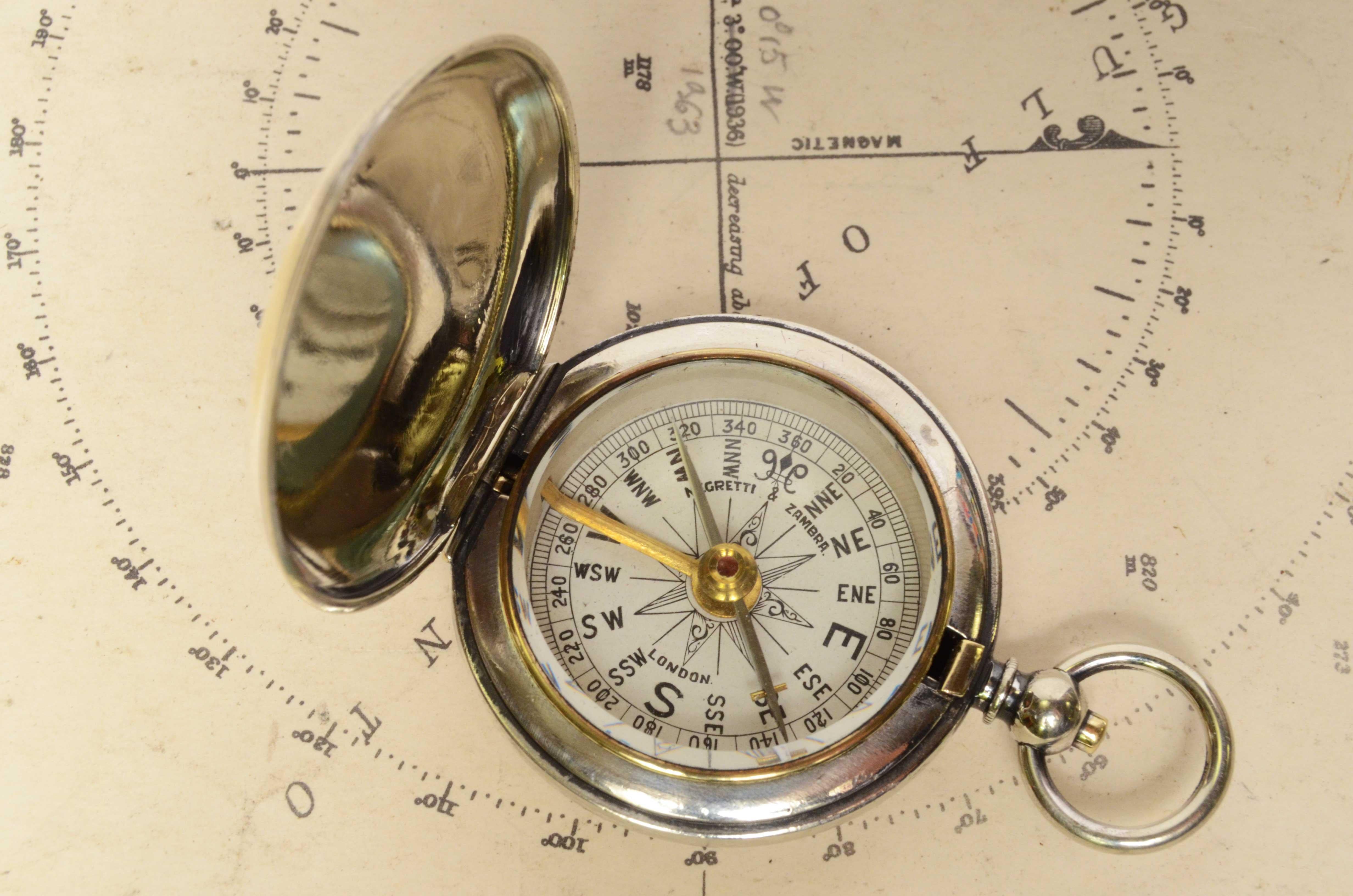 Small pocket and travel compass made of chromed brass, supplied to British army officier during the First World War. Compass in the shape of a pocket watch, equipped with a lid with snap closure with release button inside the ring, the instrument