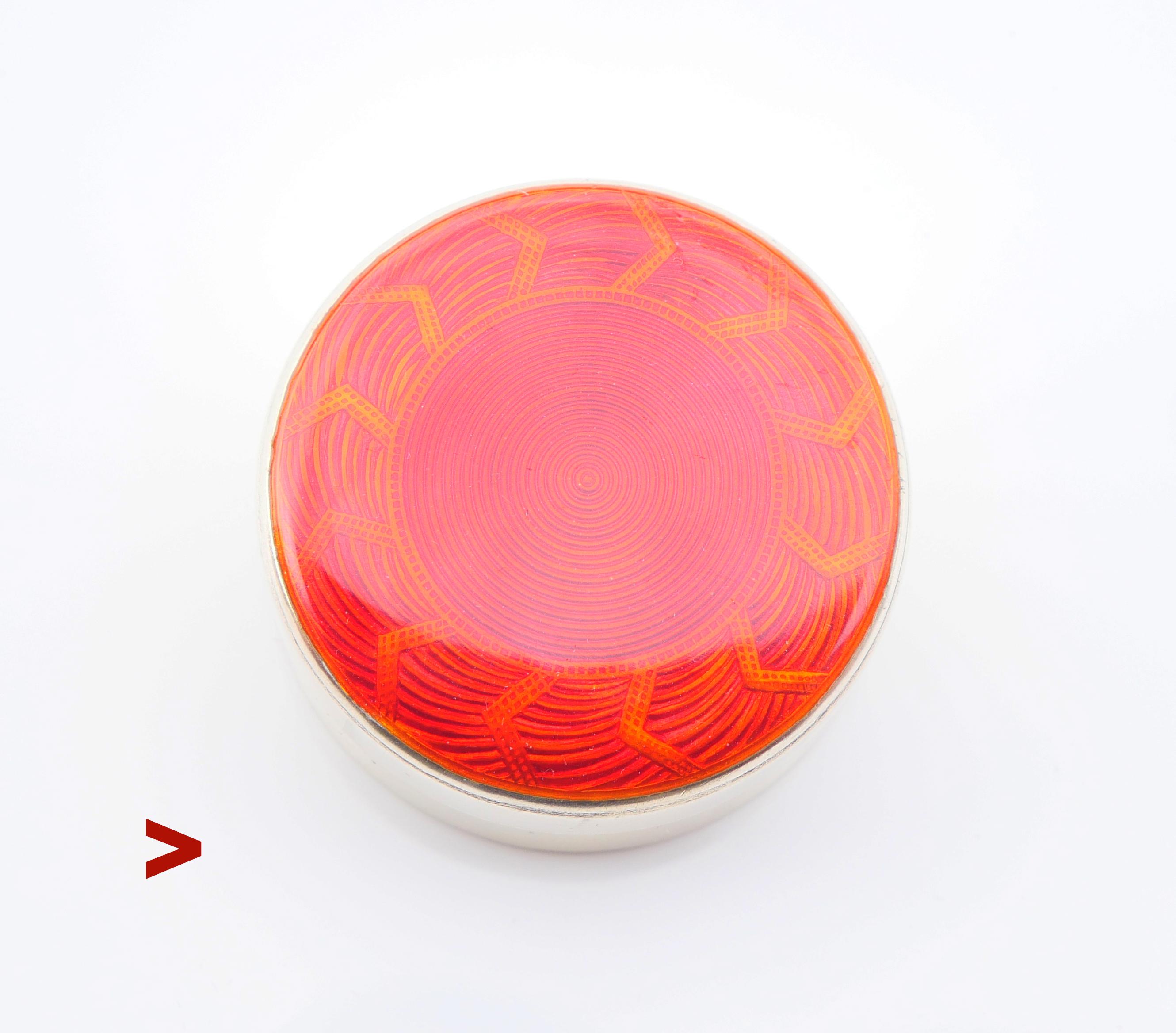 Caja de tocador sueca de plata dorada esmaltada de formas elegantes, de la época Art Déco, con un adorno de un sol que estalla en rayos ardientes bajo un esmalte guilloché rojo translúcido. Tiene un aspecto maravilloso a la luz del día. Símbolo  > 