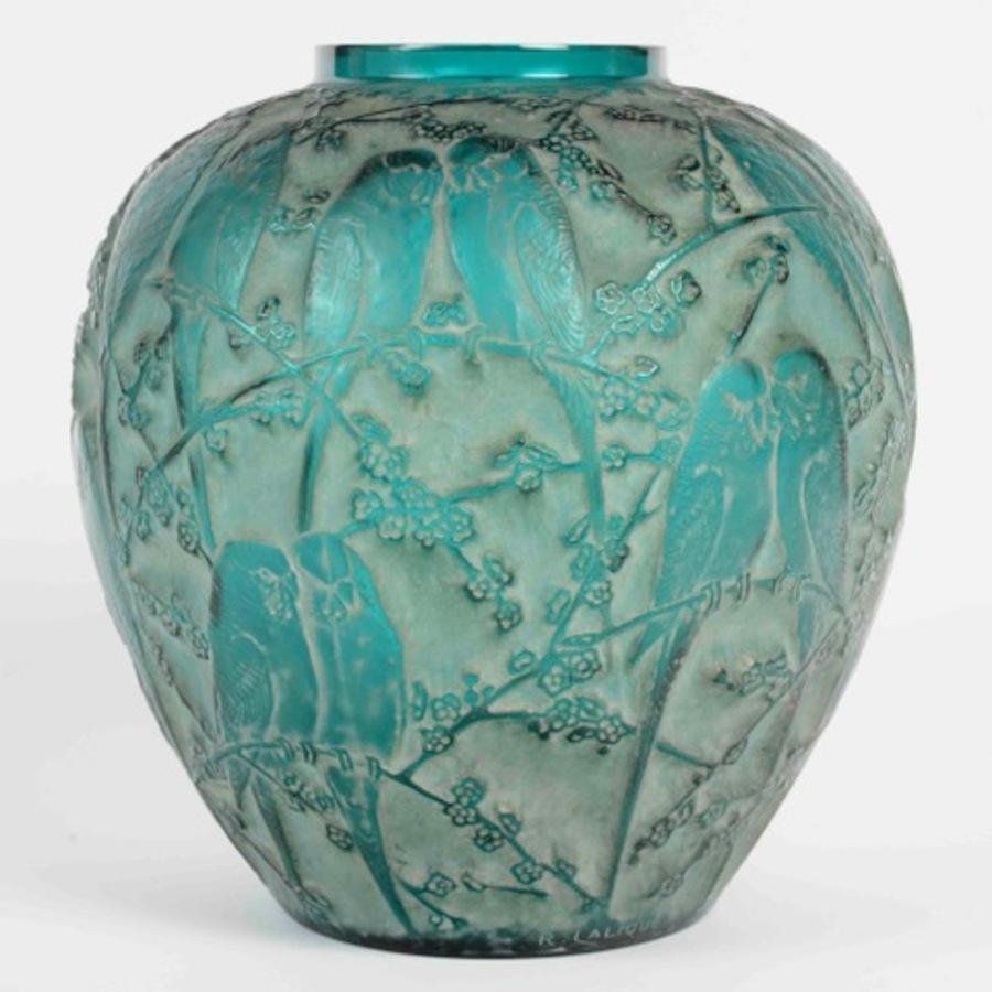 <<Parakeets>> vase in molded-pressed green-tinted glass, enhanced with an original white patina.

Model created in 1919.

Decorated across its entire surface with a motif of pairs of parakeets perched among foliage.

Dimensions: H 25.5 cm H 10