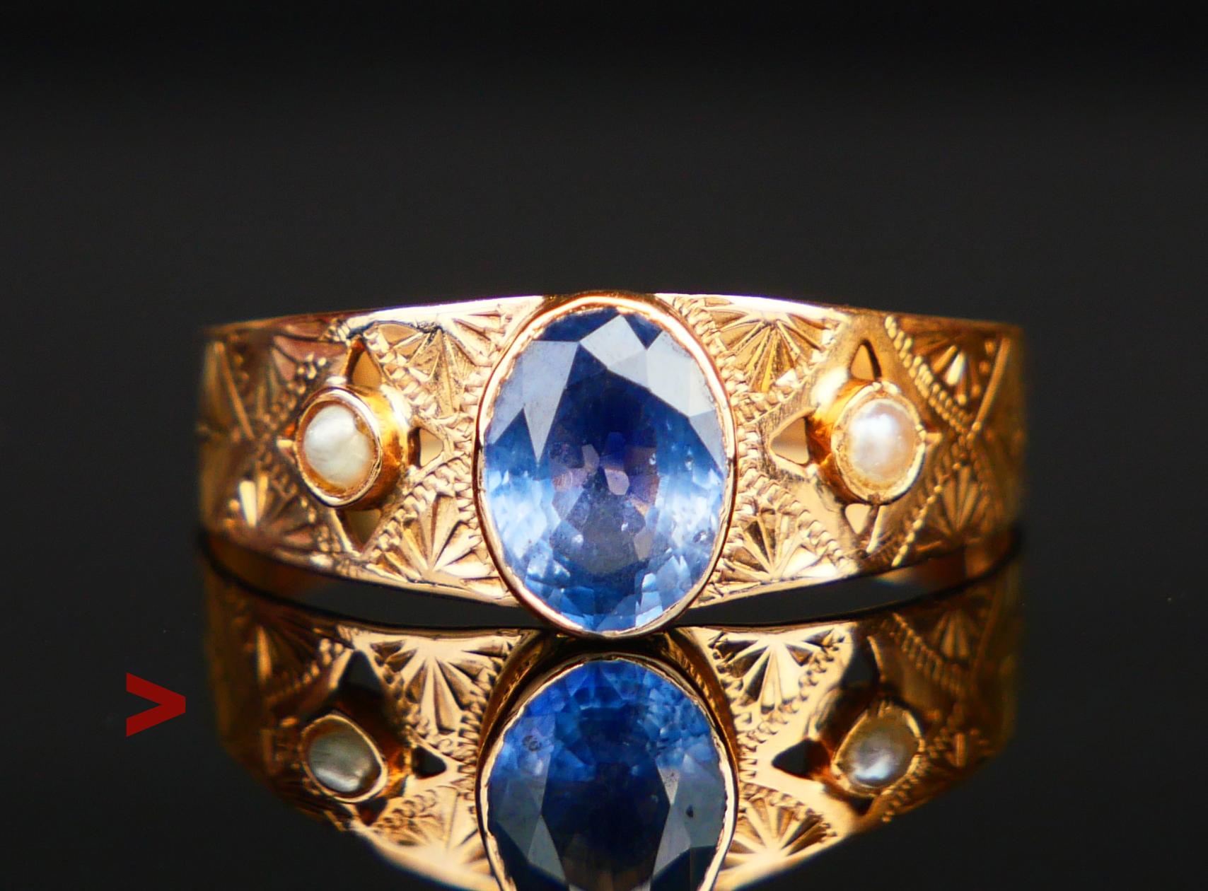 Ein Ring mit handgravierten Ornamenten mit einem eingefassten natürlichen Saphir von blauer Farbe im Ovalschliff 6,75 mm x 5 mm  x 3 mm tief / ca. 1 ct. akzentuiert mit zwei natürlichen schwedischen Flussperlen Ø je 1,75 mm. Der Saphirstein weist