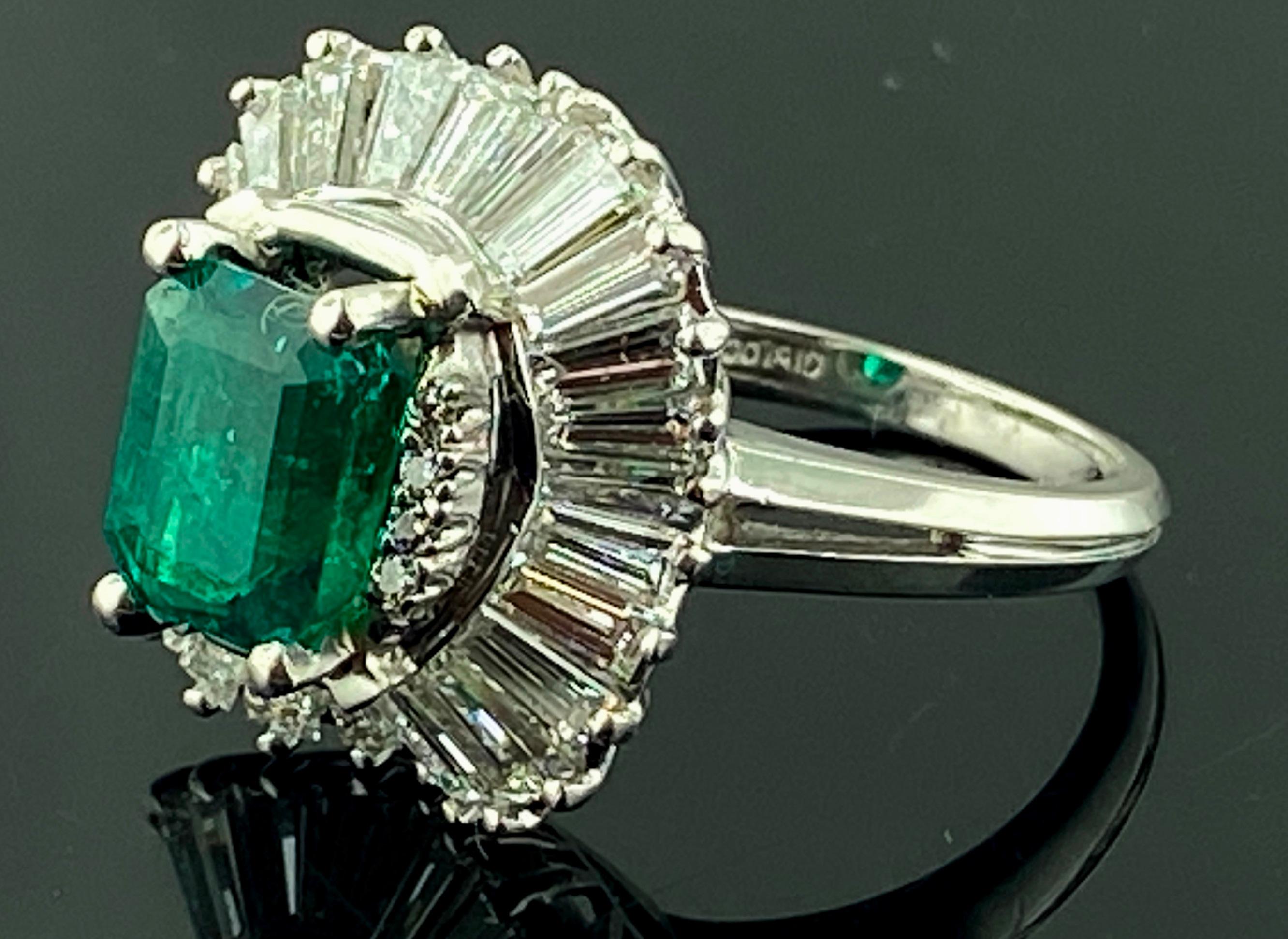 In Platin gefasst ist ein 1,92 Karat schwerer Smaragd im Smaragdschliff, flankiert von 8 runden Diamanten im Brillantschliff, umgeben von 28 Diamanten im Baguetteschliff mit einem Gesamtgewicht von 1,50 Karat.  Farbe ist F-G, Klarheit ist VVS-2. 