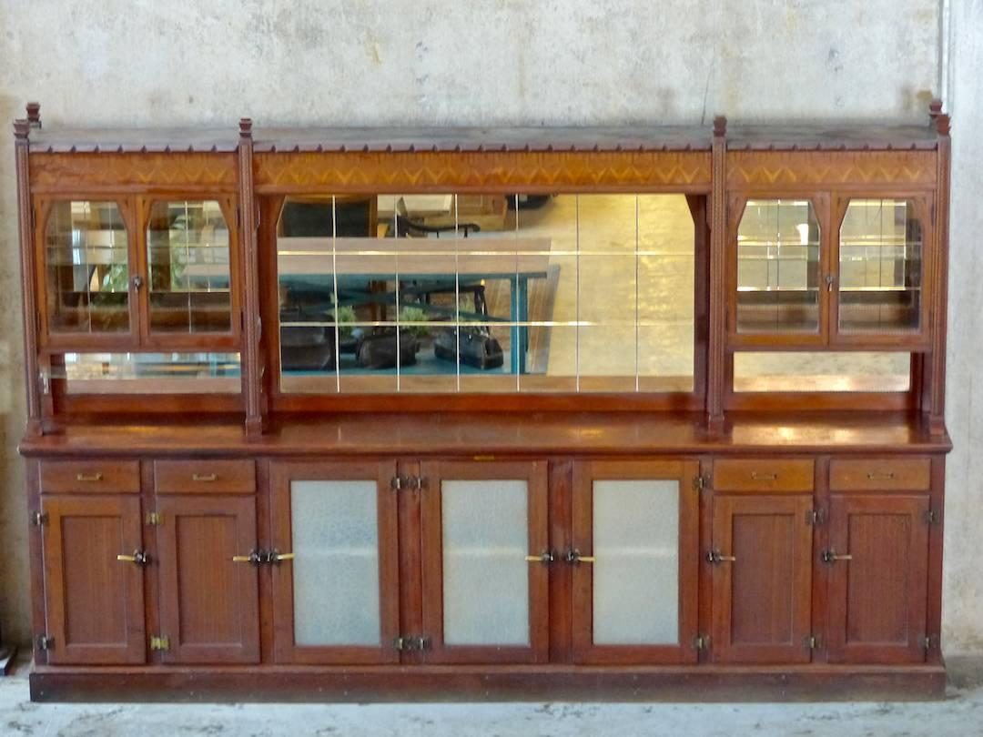 A 12-foot wide, two-piece bar/cabinet designed and built in the 1920s by Gray, McLean and Percy of Portland, Oregon. A prime example of chip-carved walnut as well as marquetry work. Cut glass decorative details and solid brass hardware complete this