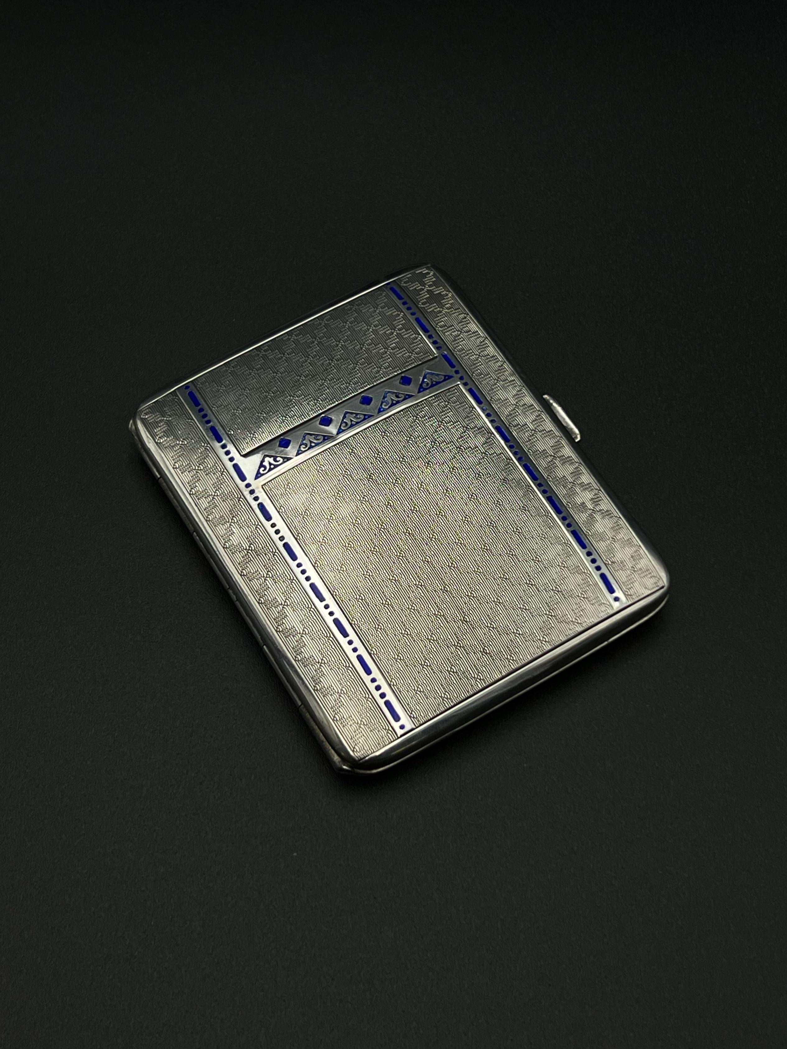 Impresionante pitillera antigua de plata y esmalte de elegante estilo Art Déco, de los años 1920-1930. Fabricada en plata fina maciza noruega del 830, con exquisitos detalles de esmalte y dorado de oro de 24 quilates en el interior.

Lleva el sello