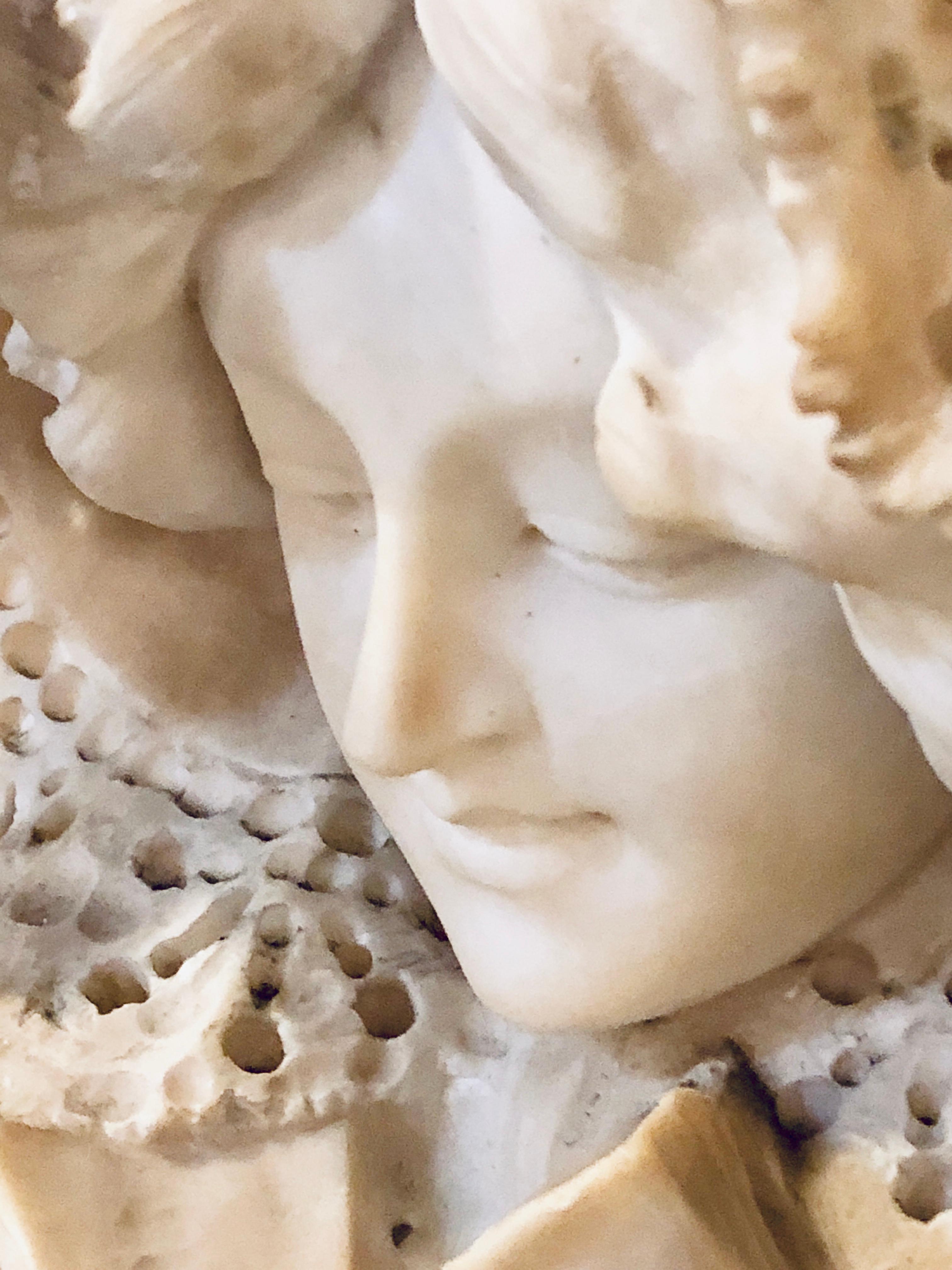 An 1920 alabaster bonnet top bust of a woman. This finely chiseled bust depicts a beautiful young woman in a pierced bonnet sitting on a small pedestal. All sold separately.