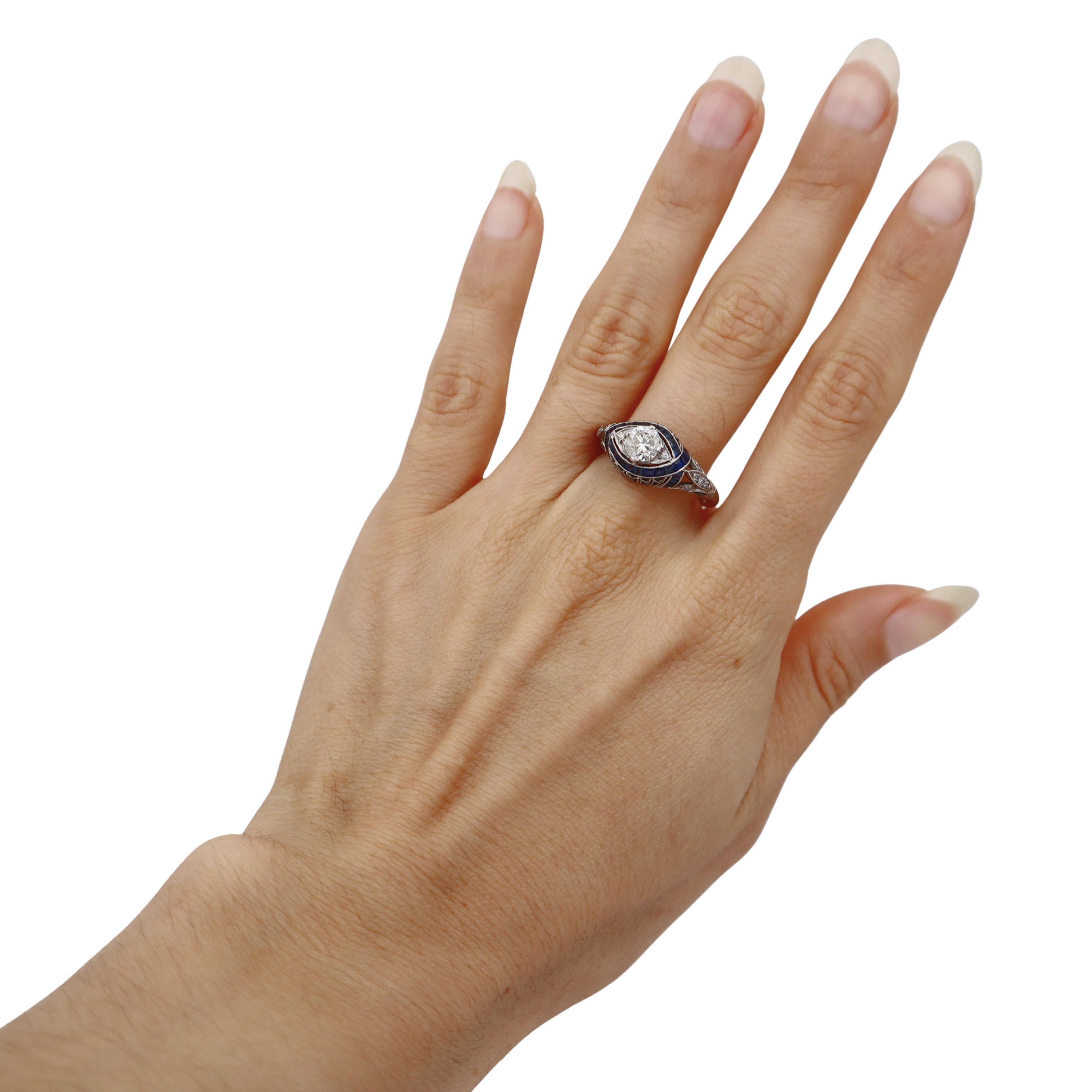 Este exquisito anillo Art Decó de filigrana muestra la maestr�ía artesanal de la época en lustroso platino, con un hermoso diamante central de 0,75 quilates complementado con 0,16 quilates de diamantes de acento y 0,60 quilates de vibrantes zafiros