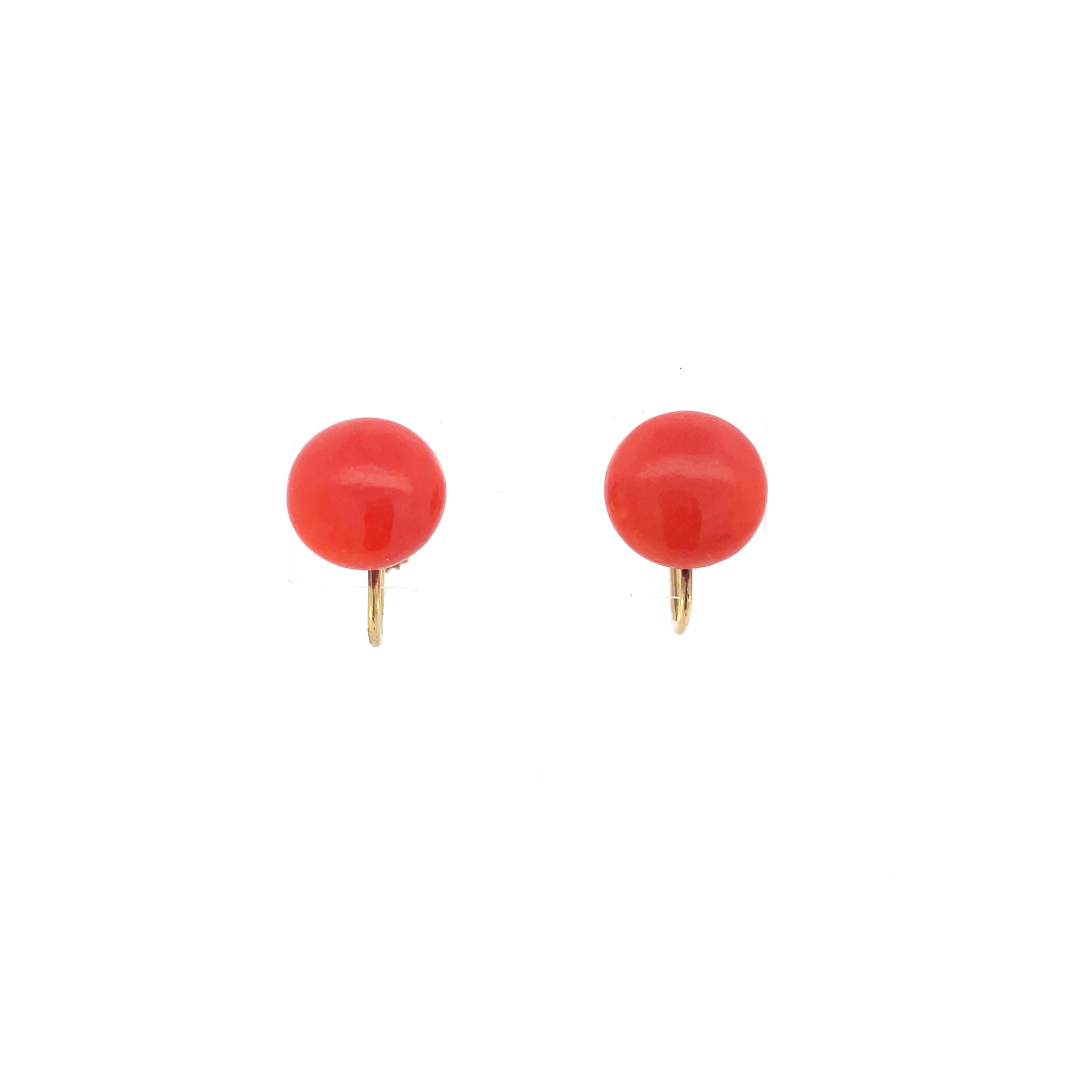 This is a timeless pair of early Art Deco screw-back earrings crafted in 18K yellow gold that showcases two natural coral buttons! These beautiful ocean gems were harvested in the 1920s, completely natural and undyed, and are a beautiful orange-red