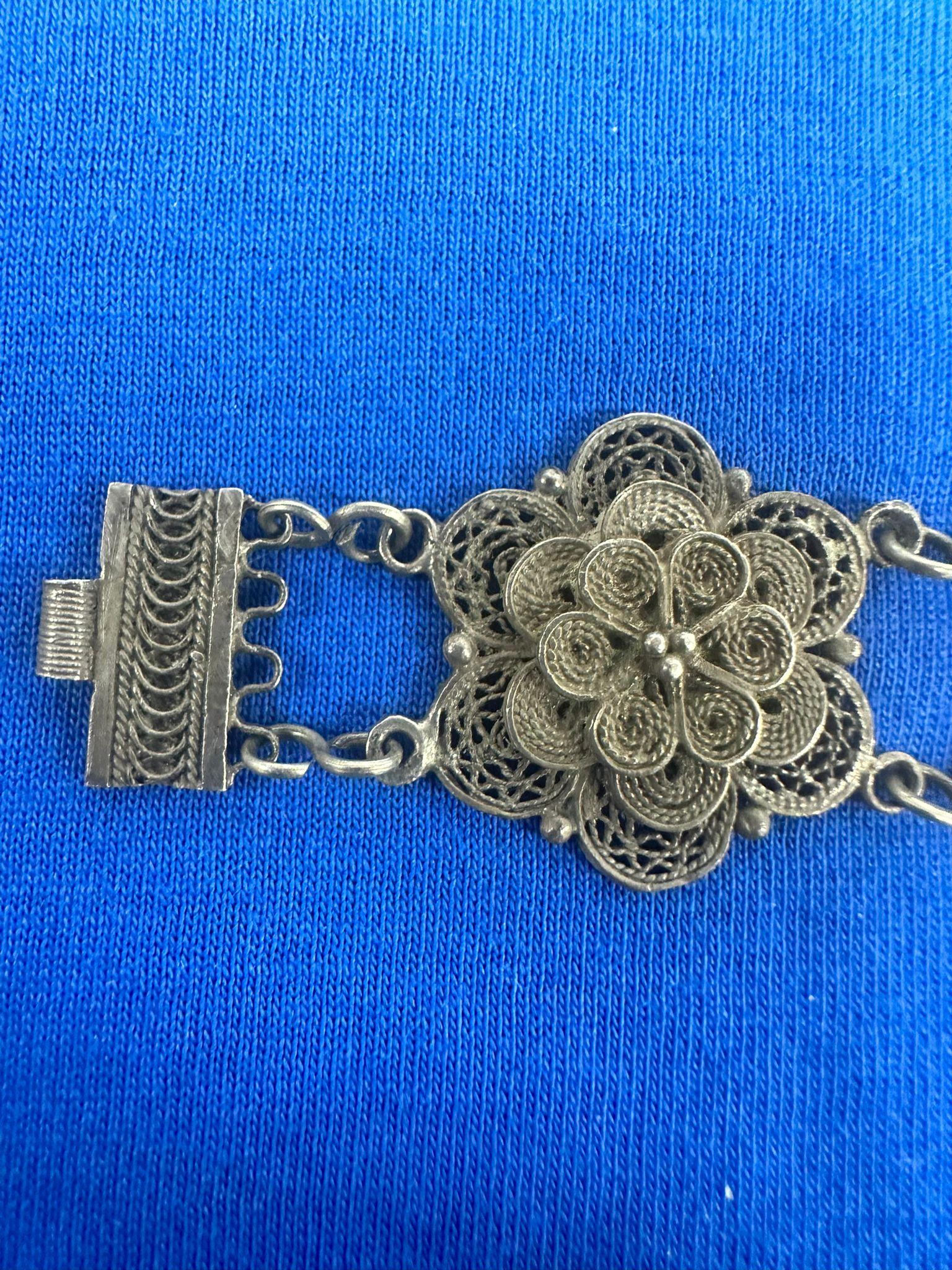 This exquisite handmade silver filigree bracelet, created circa 1920 at the renowned Bezalel School of Arts and Crafts in Jerusalem, exemplifies the intricate artistry and cultural fusion that defined early 20th-century Judaica. The bracelet