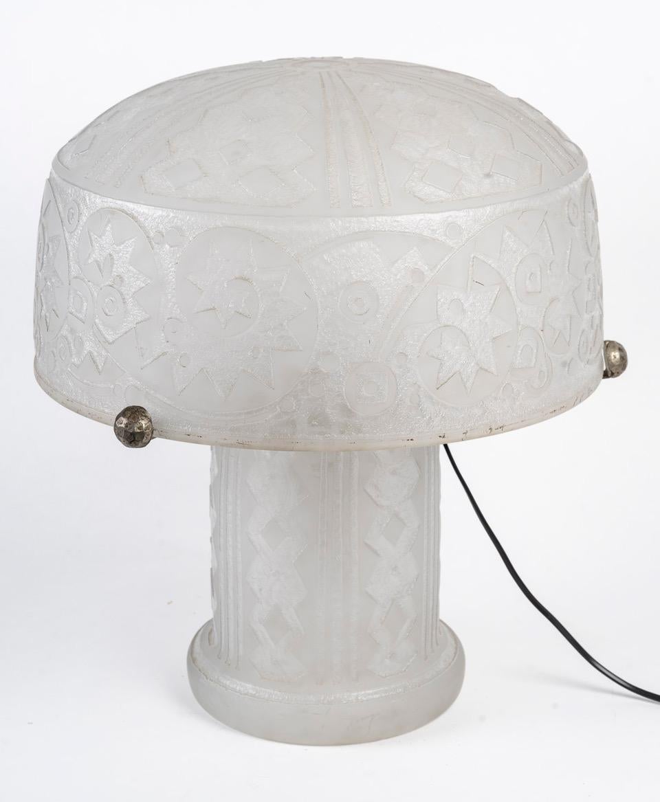DAUM Nancy France Table lamp, circa 1920  

Table lamp, colorless glass with acid-etched decoration of stylized geometric motifs. 
The semi-spherical lampshade is held by a wrought-iron three-armed metal structure terminating in a small hammered and