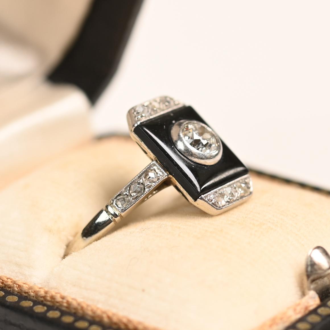 Un llamativo anillo Art Déco, hecho a mano en platino hacia 1920, muestra la elegancia y precisión intemporales de la época. En su centro hay un diamante de talla europea antigua engastado en bisel que pesa aproximadamente 0,20 quilates, graduado en