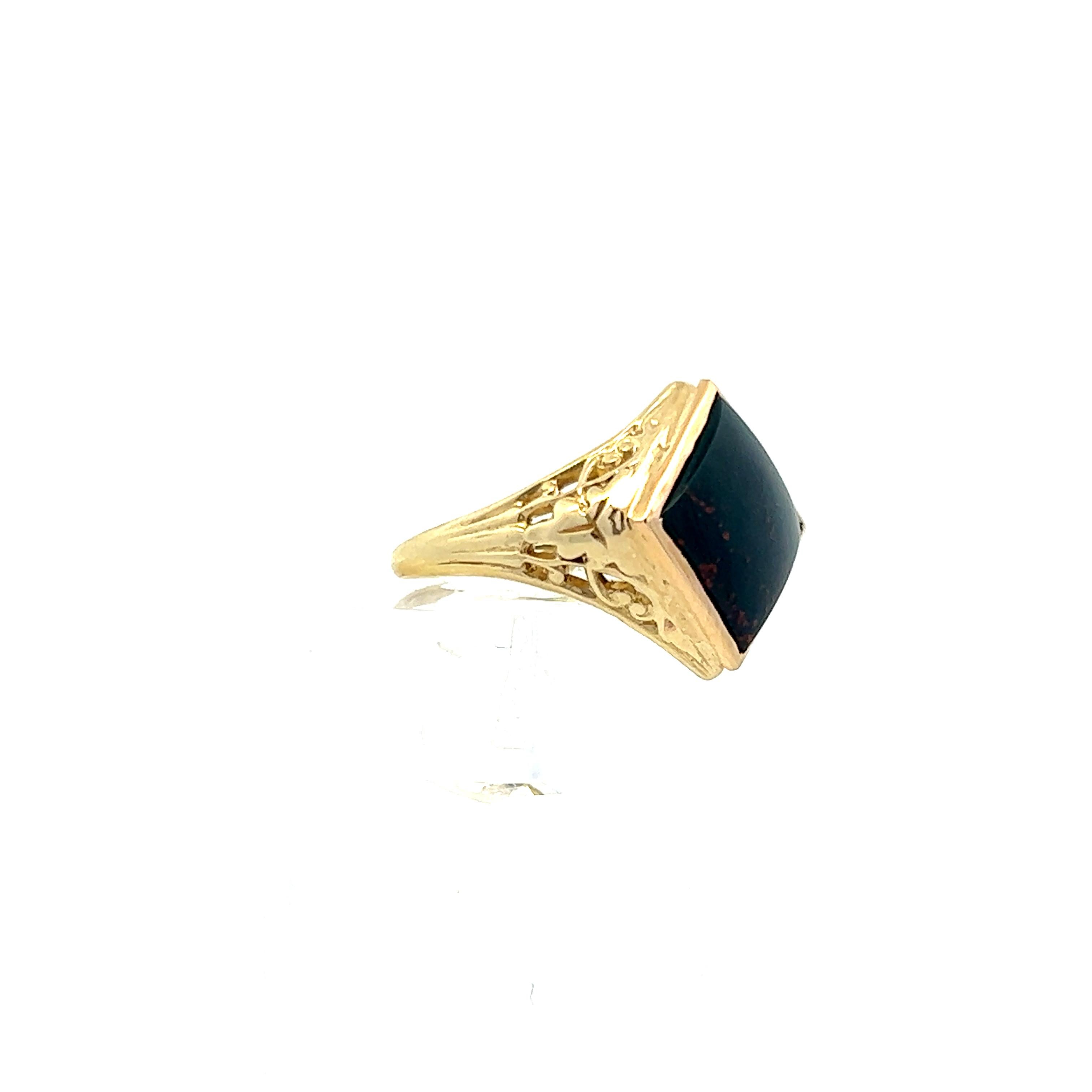 This elegant ring is a 1920s bloodstone Edwardian gold filigree ring. The ring features a large, square cut, bloodstone cabochon as the center stone with beautiful gold filigree sides. The combination of dark green bloodstone and gold is simple yet