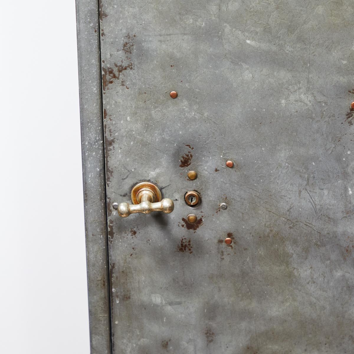 1920s English industrial metal storage cabinet. With a slightly arc-shaped top,  ribbed metal door handle and streaked, mottled texture, the piece has a cool and industrial feel. A fabulous way to incorporate a grittier element with a rich metallic