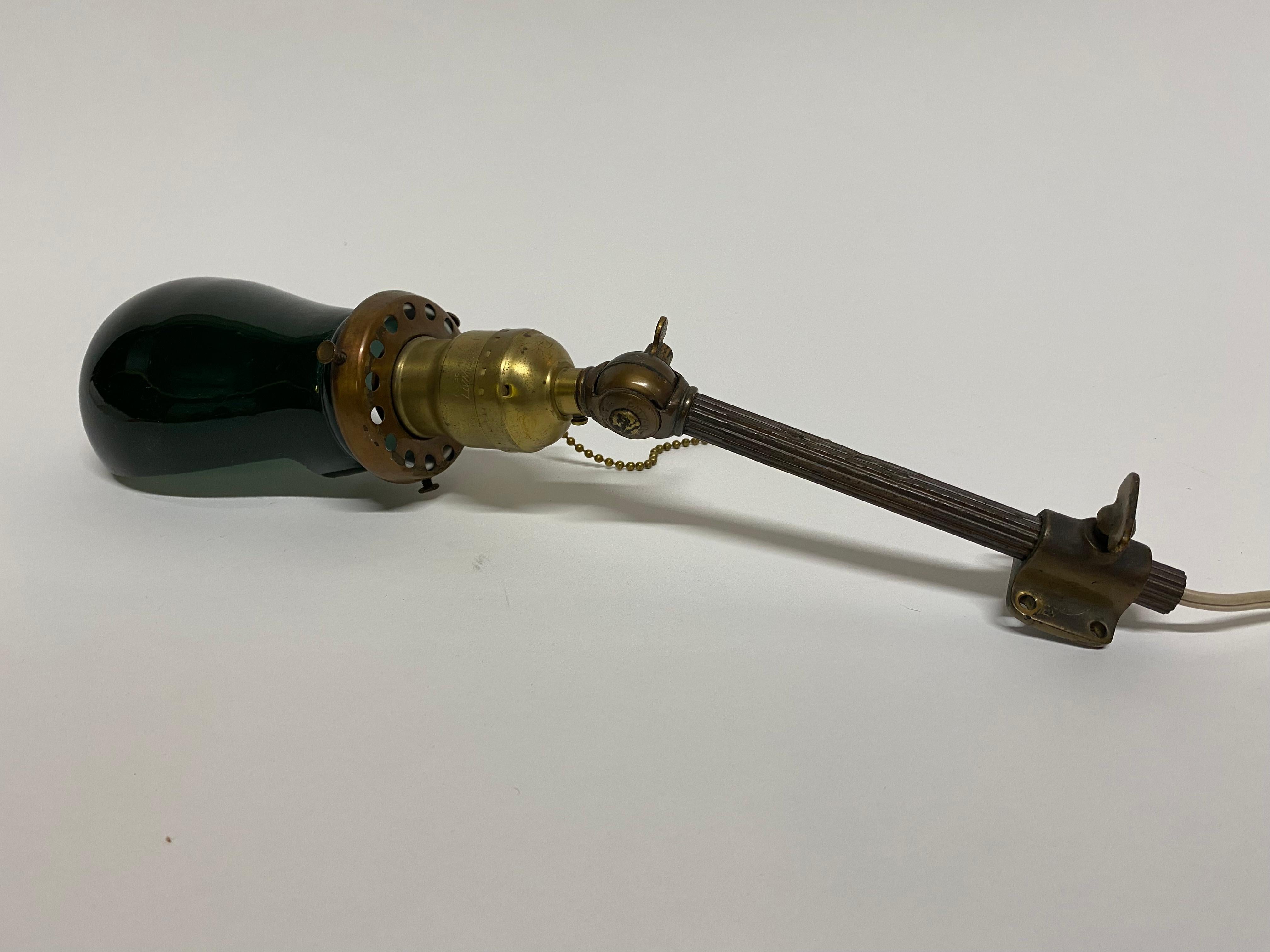German articulated Emeralite Fostoria style work light, circa 1920. Needs to be fixed to a wall or wood molding. Green exterior and white interior glass shade. Adjustable height and extension fluted brass arm. The shade is acid stamped, Germany.