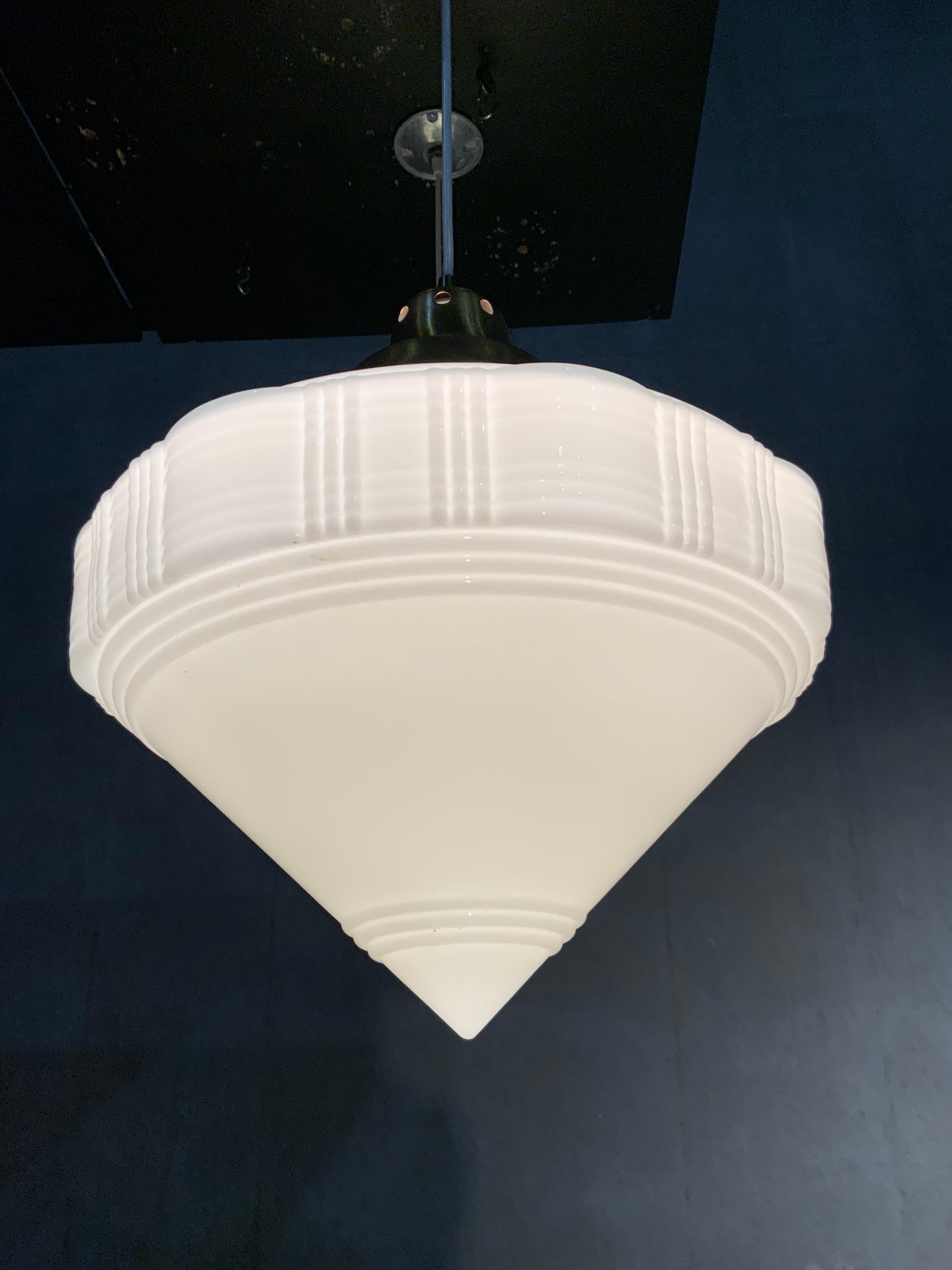 We have a set of 8 of these oversized Art Deco milk glass pendants salvaged from a bank in Eastern USA. They are on brass fitters and simple cable for easy adjustment and a cleaner refined look. 

These are a very nice unique shade.