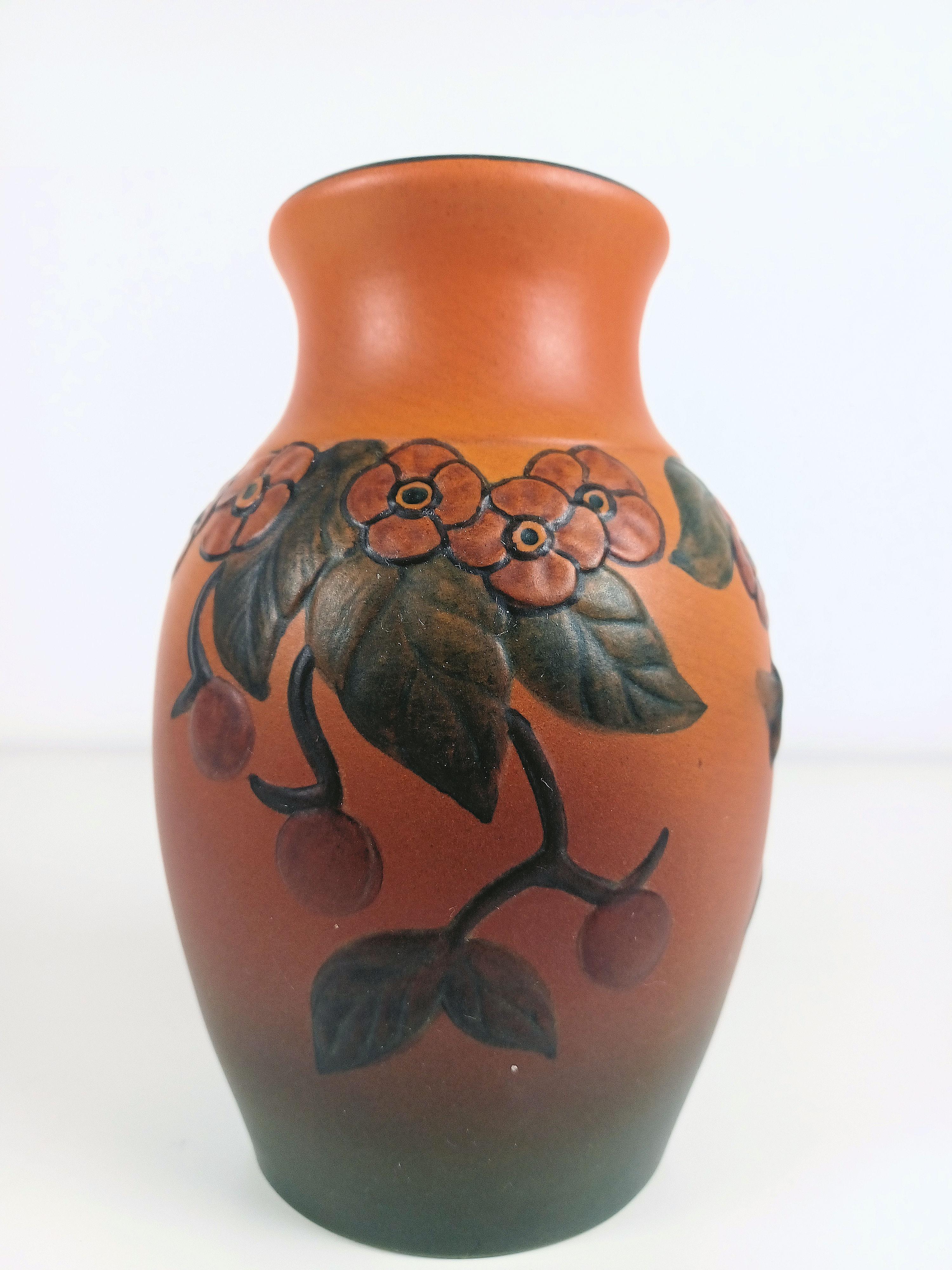 Handgefertigte dänische Vase im Jugendstil mit Blumendekor von P. Ipsens Enke

Die handgefertigte Jugendstilvase wurde 1927 von Axel Sørensen entworfen und ist mit  Blüten, Blätter, Beeren und eine einzelne Biene auf dem Weg zu einer Blüte. 

P.