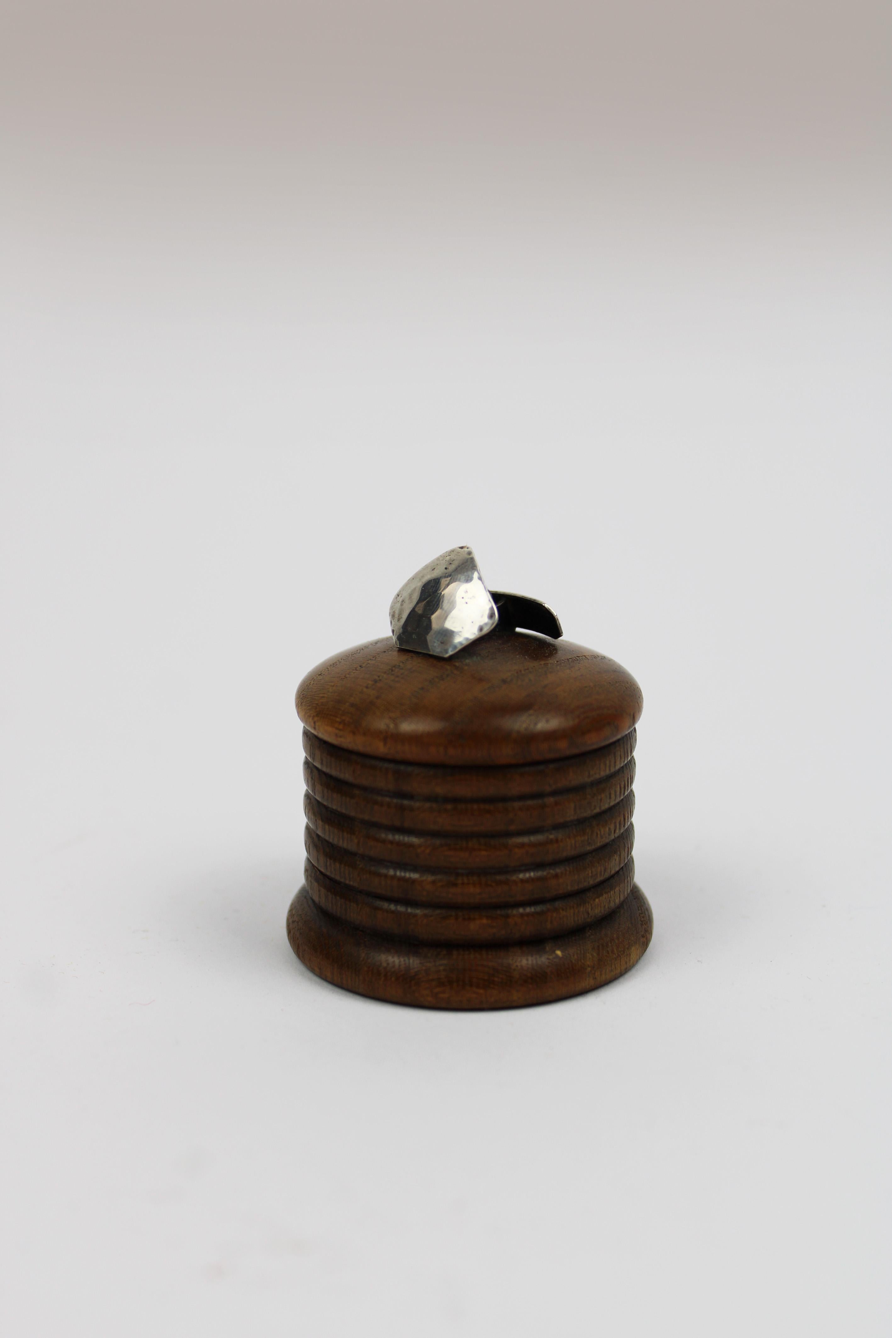 This charming small round treen cufflink box from the 1920s is a delightful example of French craftsmanship. The box is topped with a silver cufflink, adding a touch of elegance and sophistication to its design. Made in France, this piece is not