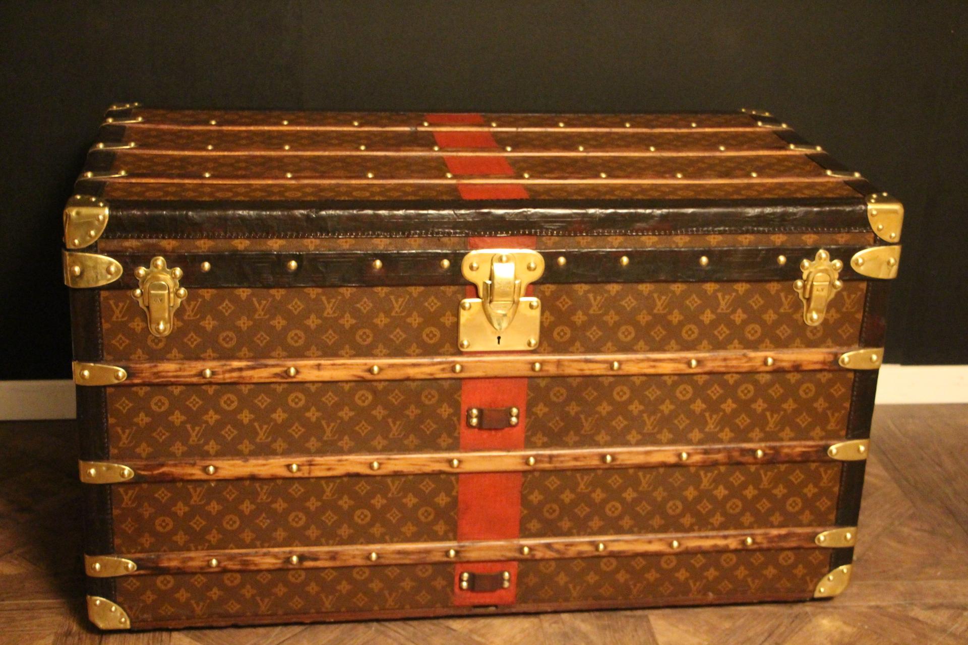 This superb Louis Vuitton steamer trunk features stenciled monogram canvas, deep chocolate color leather trim, LV stamped solid brass locks and studs as well as solid brass side handles and brass corners. It features a customized red painted stripe