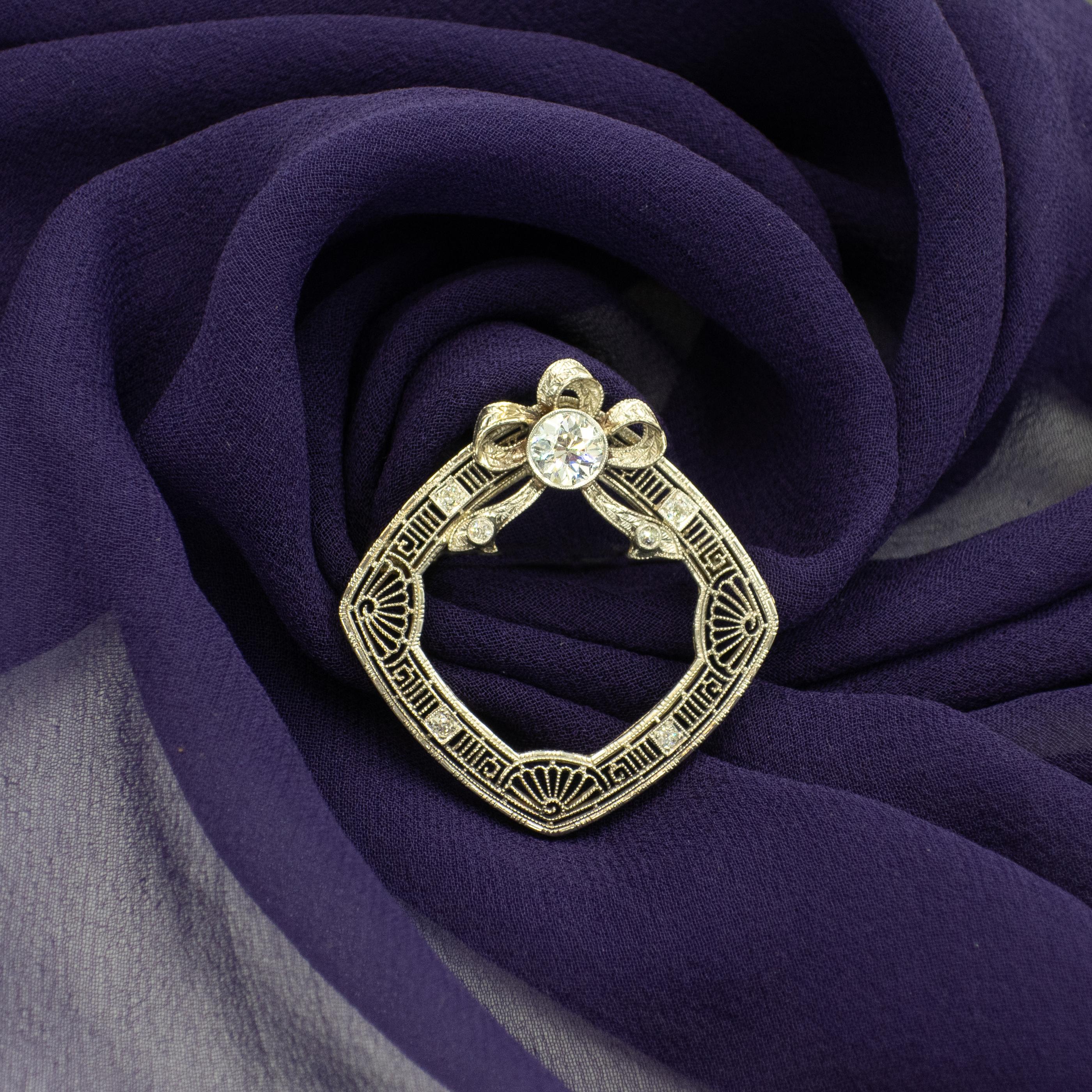 1920s diamond filigree Brooch. White gold filigree wreath with a ribbon bow on top, 7 diamonds on the wreath. The center Old European cut diamond approximate 0.70 carat in I color VS clarity set over the ribbon bow.

Approximate Gross Weight: 4.70