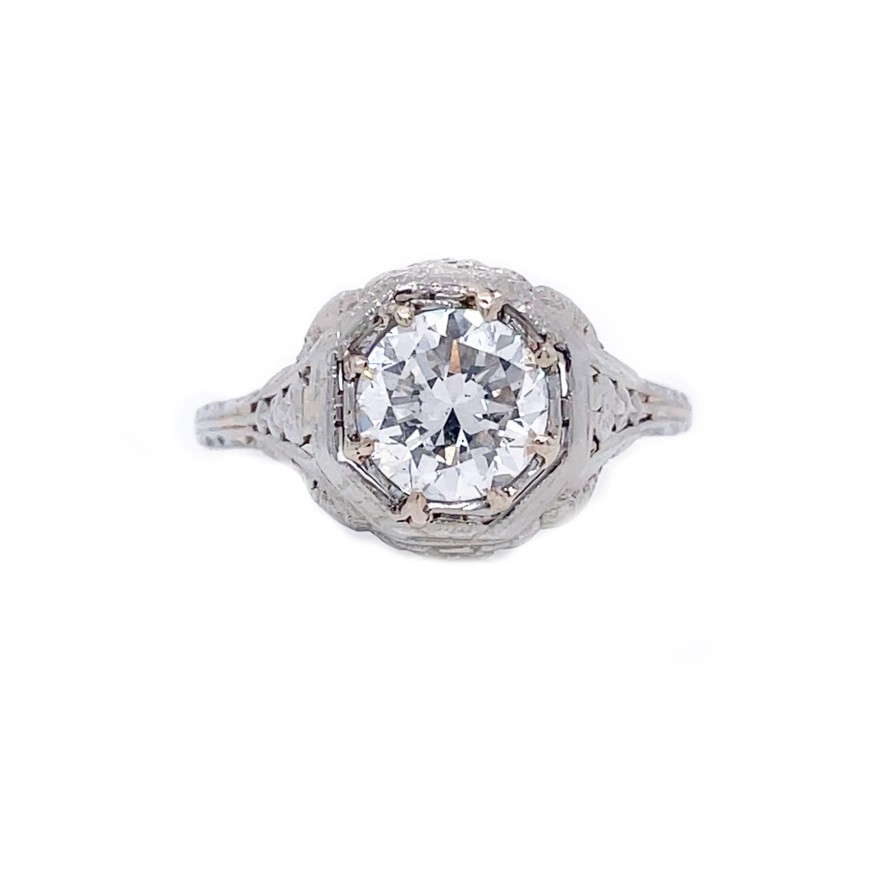 This is a breathtaking 18K white gold ring from the 1920s that showcases gorgeous filigree and a stunning bright white diamond! Eight prongs secure an icy white diamond that is sure to wow and is accompanied by a GIA report. This utterly charming