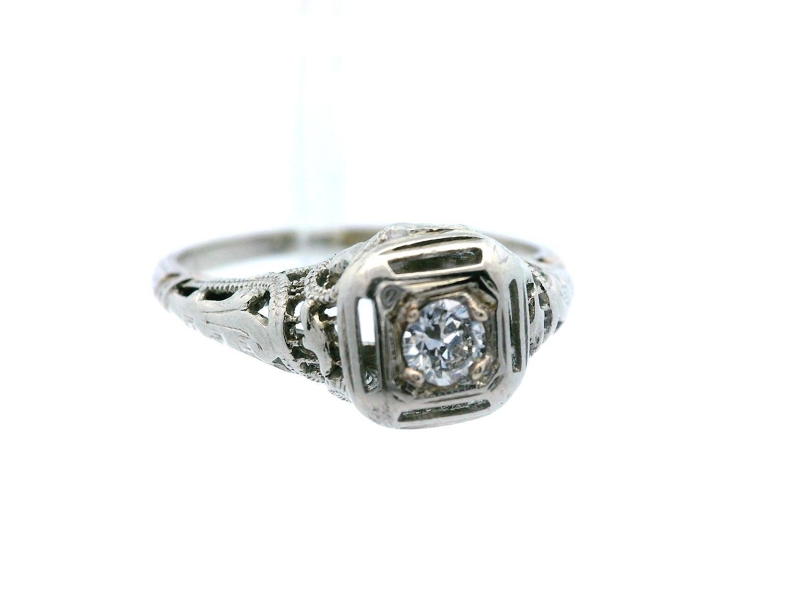 Questo splendido anello in filigrana d'oro bianco risale al periodo Art Deco degli anni '20 e mette in mostra un brillante diamante bianco al centro. Il diamante da 0,15 carati, taglio rotondo, purezza VS1, colore G, è incredibilmente brillante e si