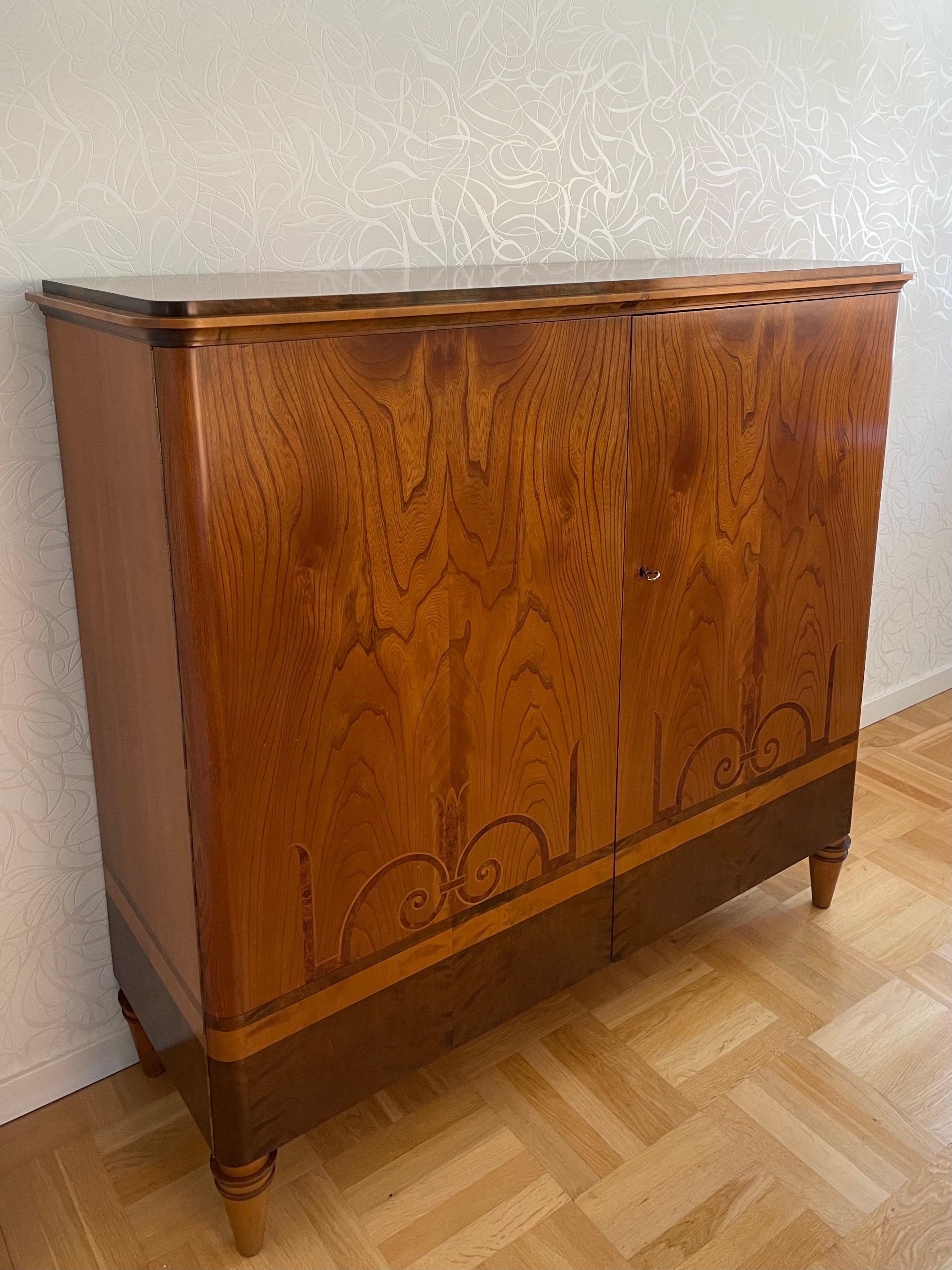 Dies ist die 1920er - 1930er Jahre schwedischen Grace Intarsienschrank zugeschrieben Carl Bergsten.
Die Platte ist mit dunkel gebeizter Birke furniert und mit einer gut gezeichneten Leiste in geraden und geschwungenen Formen verziert. Genau wie das