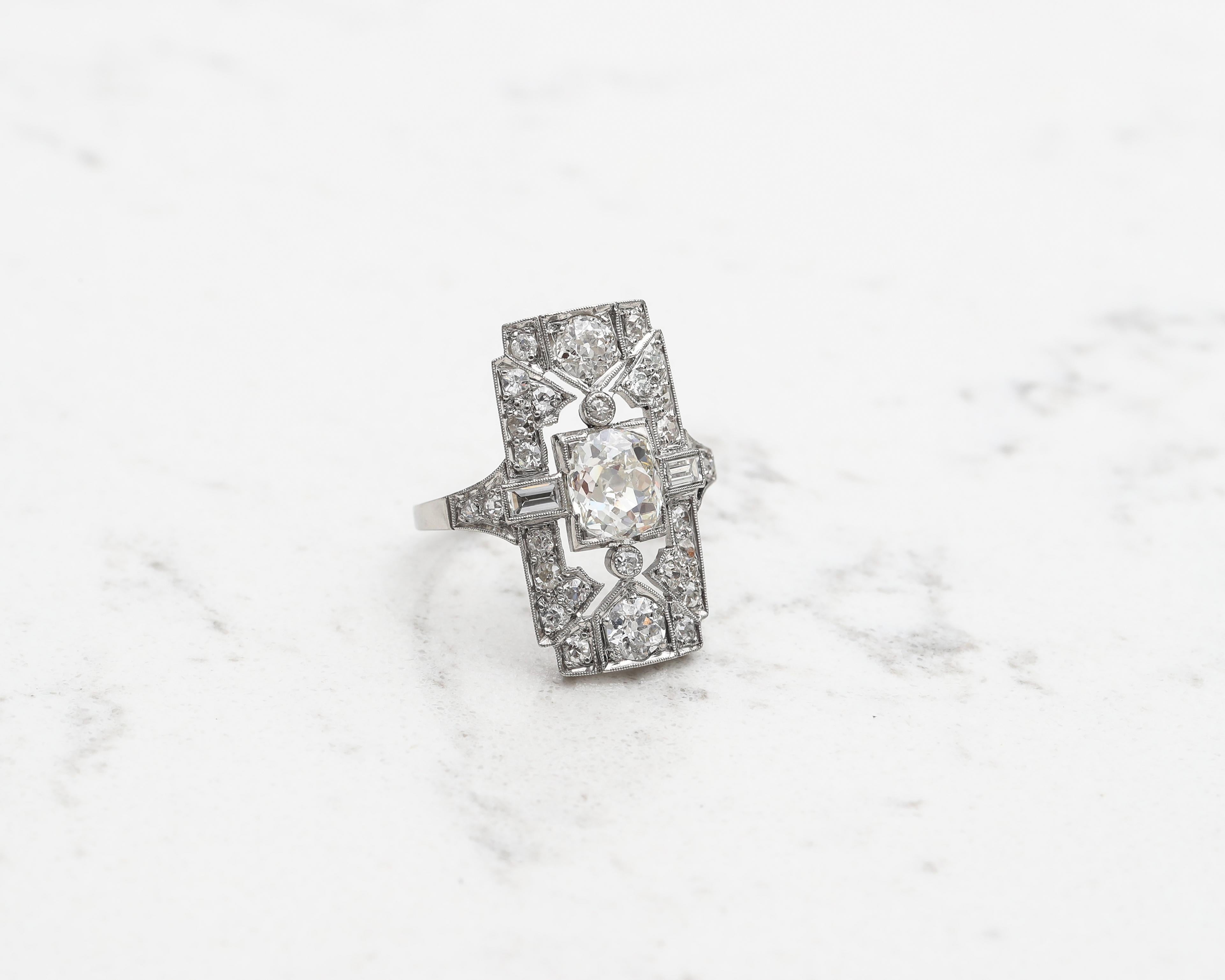 Art Deco Era 1920s Engagement Shield Ring featuring 2.40 carats of diamonds. 
Design is quite exquisite with intricate cut-out gallery and milgrain detailing around each part. Symmetrical design is seen throughout the piece. The diamonds sparkle